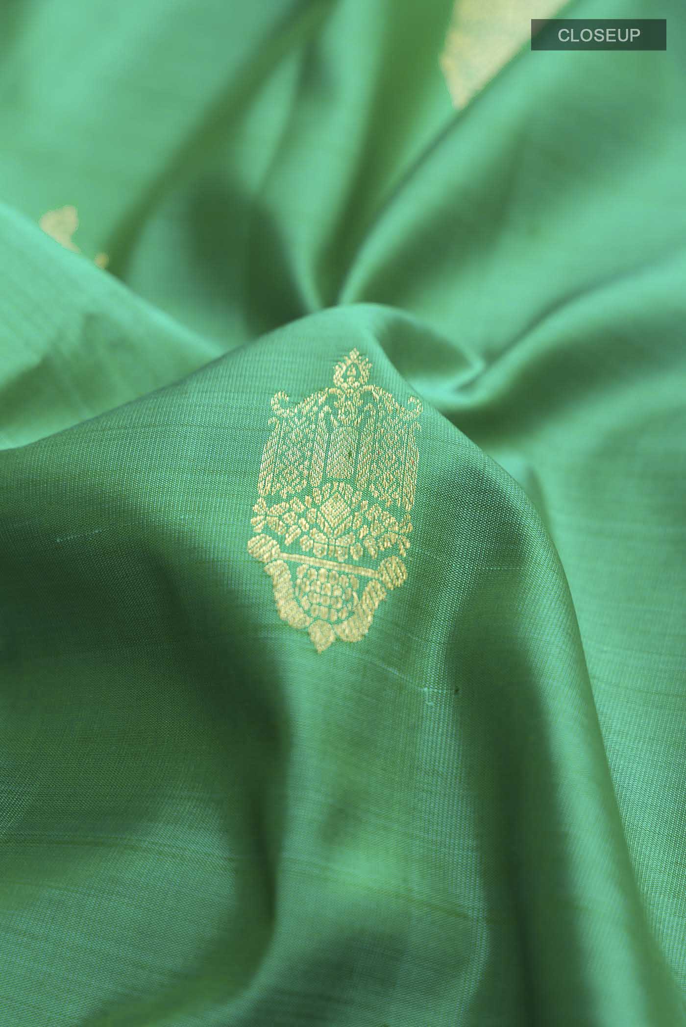 Close up of Green Kanchipuram Silk Saree with Zari Butta on the body and Zari Border displaying folds