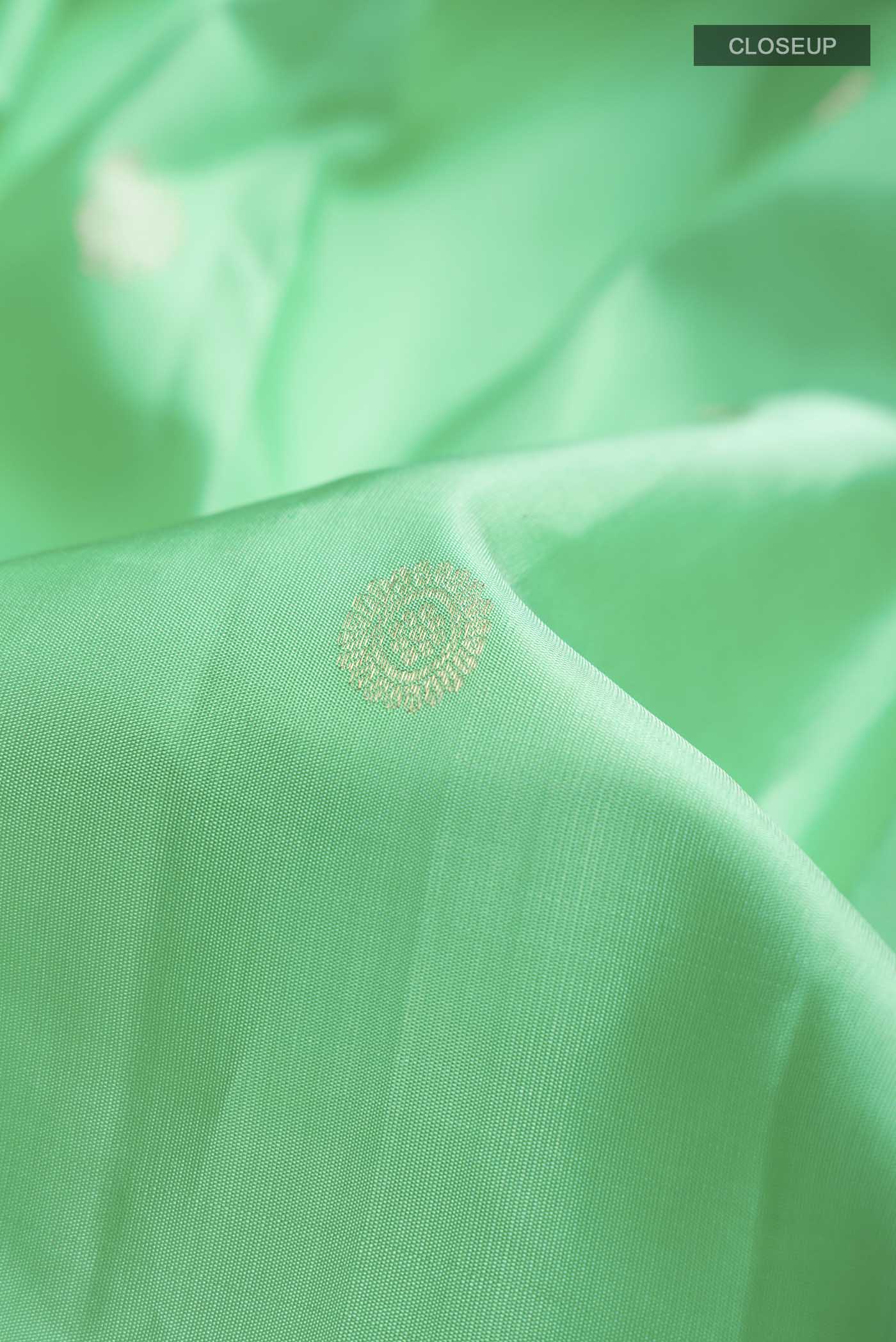 Close up of Green Kanchipuram Silk Saree with Zari Butta on the body and Zari Border displaying folds