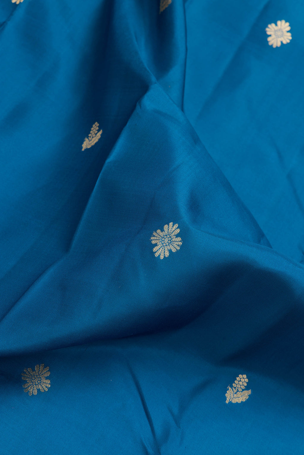 Close up of Peacock Blue Dual Tone Kanchipuram Silk Saree with Zari Butta on the body and Zari Border.  displaying folds