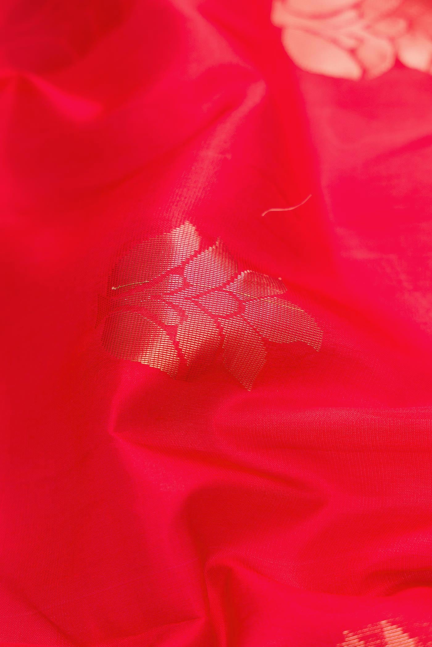 Close up of Red Dual Tone Soft Silk Saree with Zari Butta on the body and Zari Border.  displaying folds