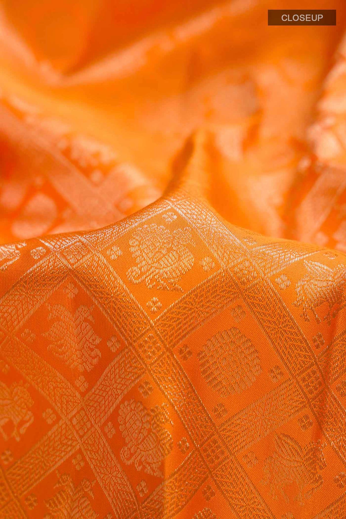Close up of Orange Kanchipuram Silk Saree with Zari Brocade on the body and Zari Border displaying folds