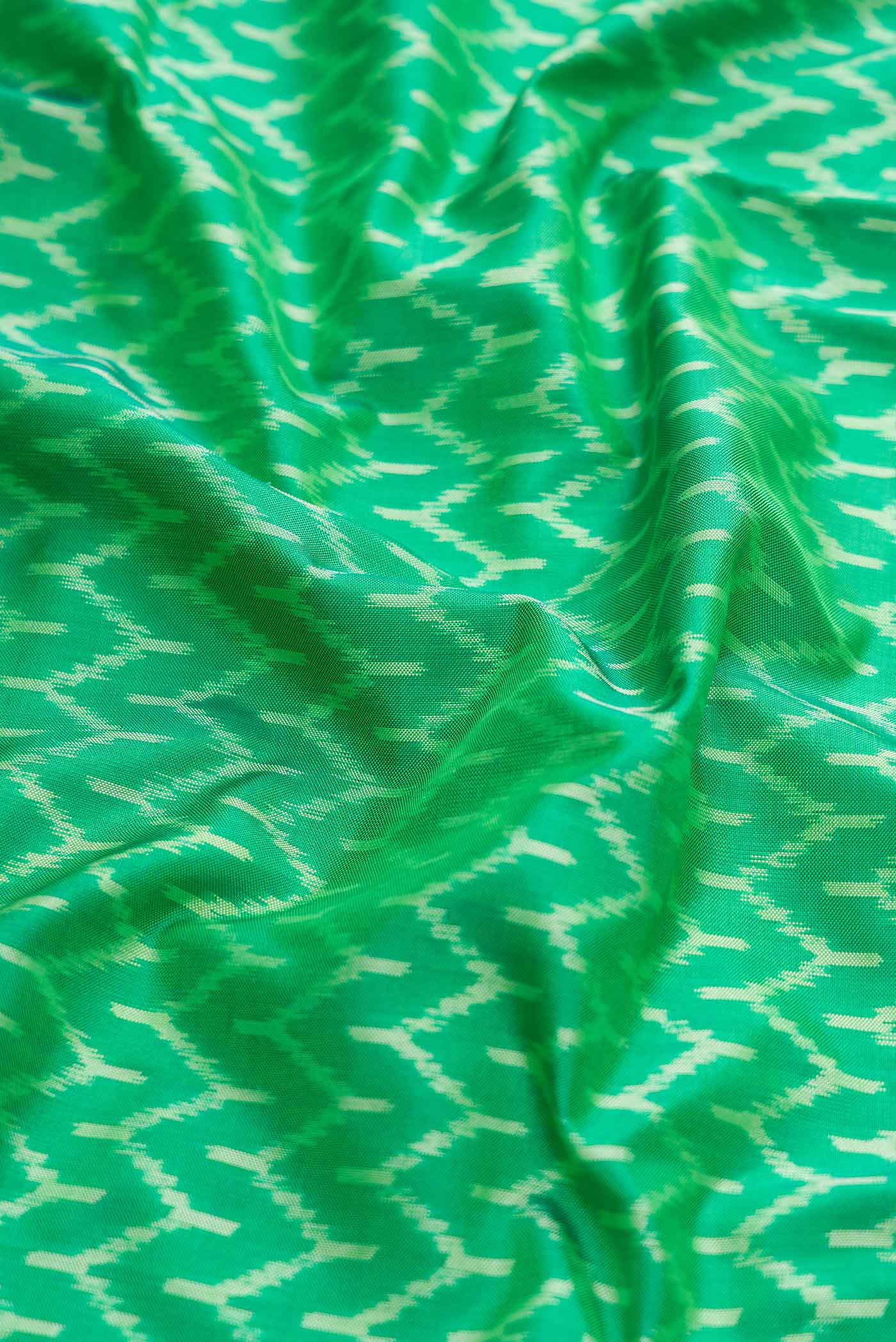 Close up of Green Dual Tone Double Ikat Saree with Ikat Print on the body and Zari Border displaying folds