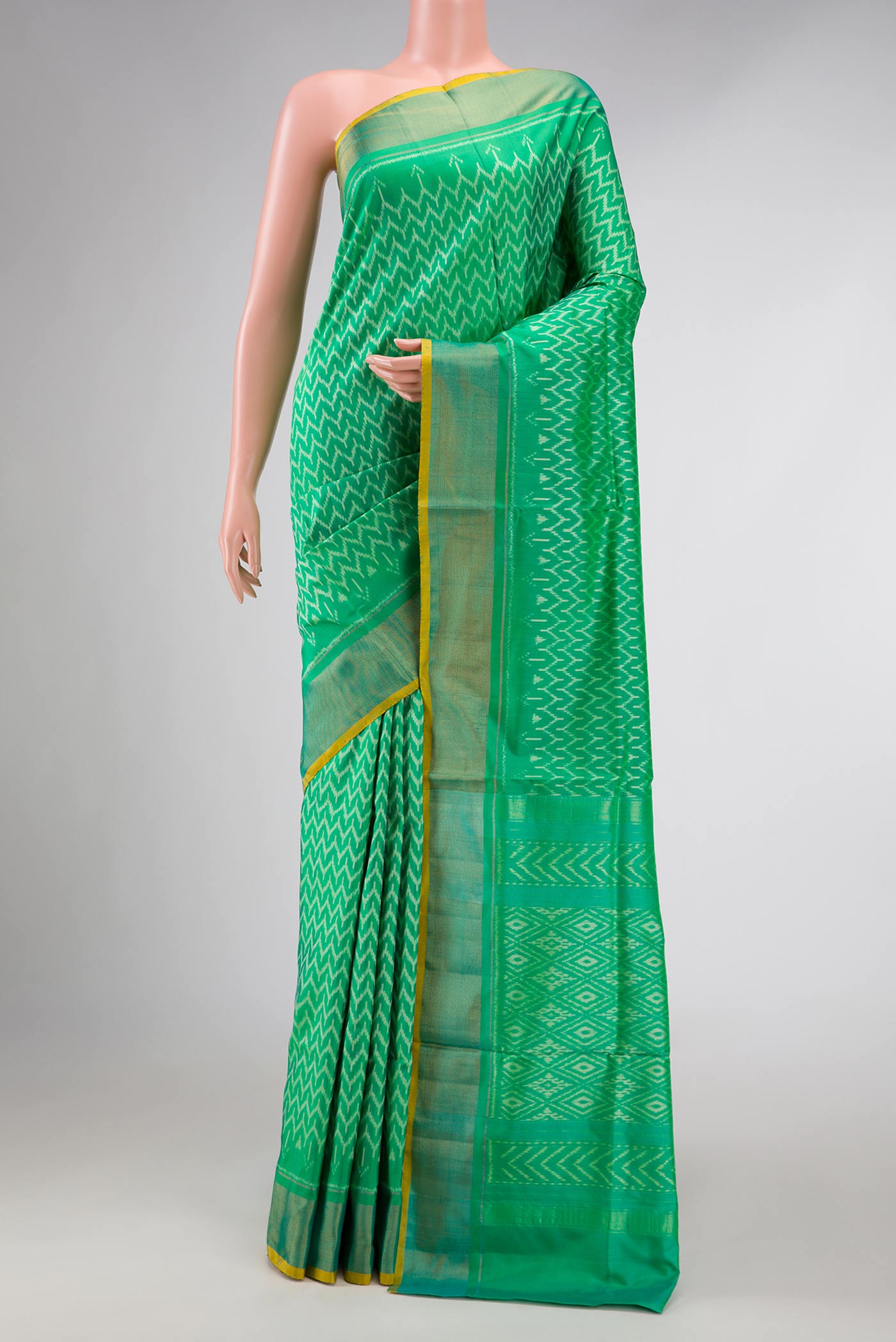Green Dual Tone Double Ikat Saree with Ikat Print on the body and Zari Border displayed on a mannequin