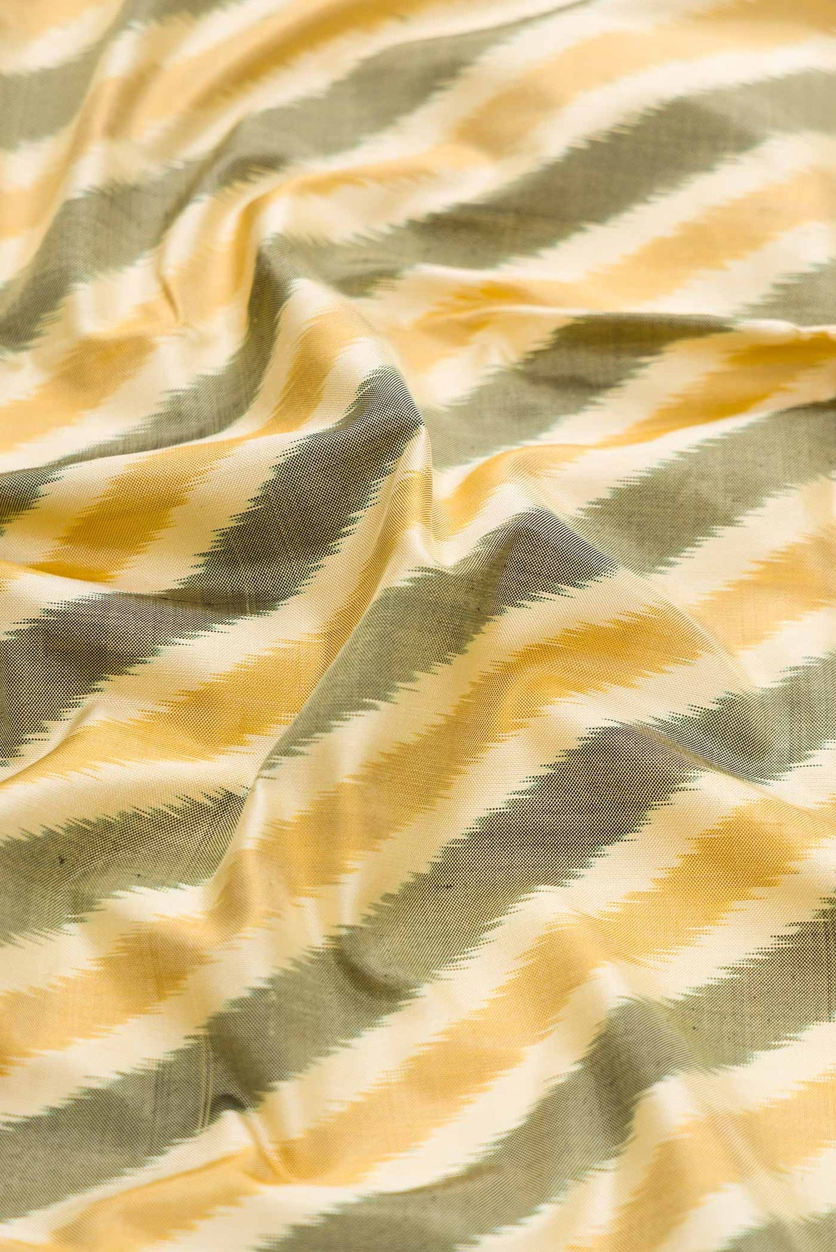 Close up of Sandal and Grey Color Double Ikat Saree with Ikat Print on the body and Zari Border displaying folds