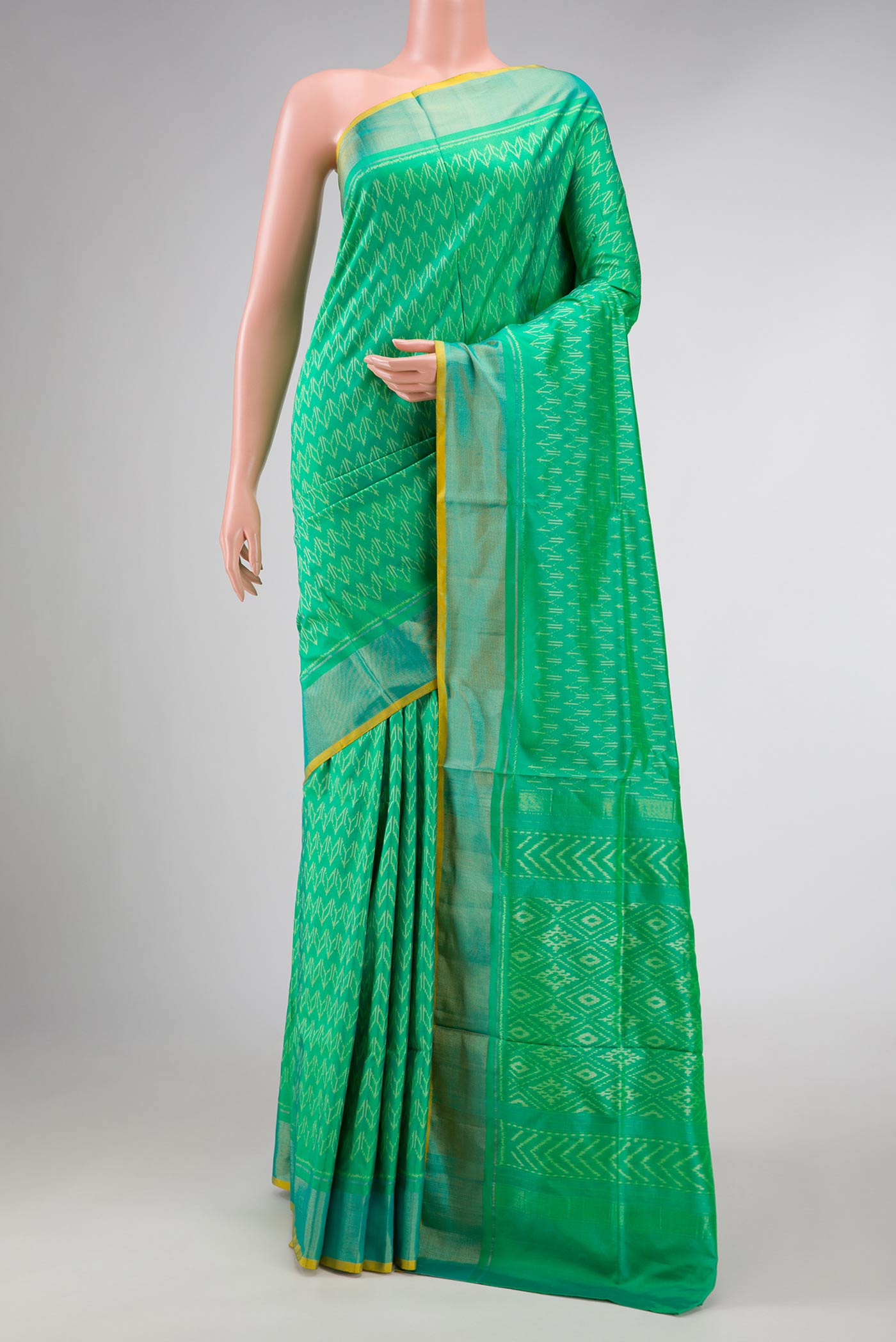 Green Dual Tone Double Ikat Saree with Ikat Print on the body and Zari Border displayed on a mannequin