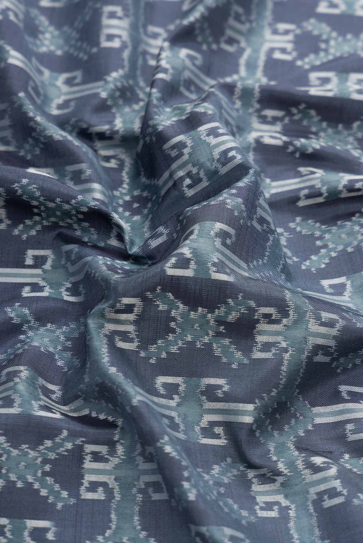 Close up of Grey Dual Tone Double Ikat Saree with Ikat Print on the body and Zari Border displaying folds