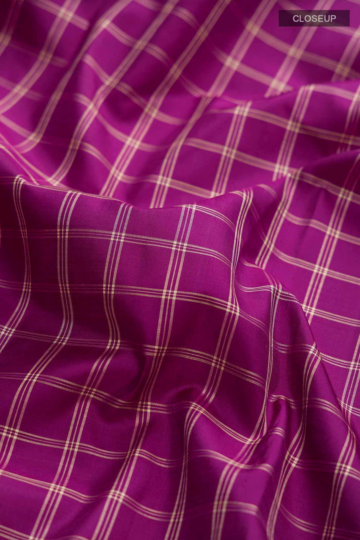 Close up of Purple Kanchipuram Silk Saree with Checked design on the body and Zari Border displaying folds