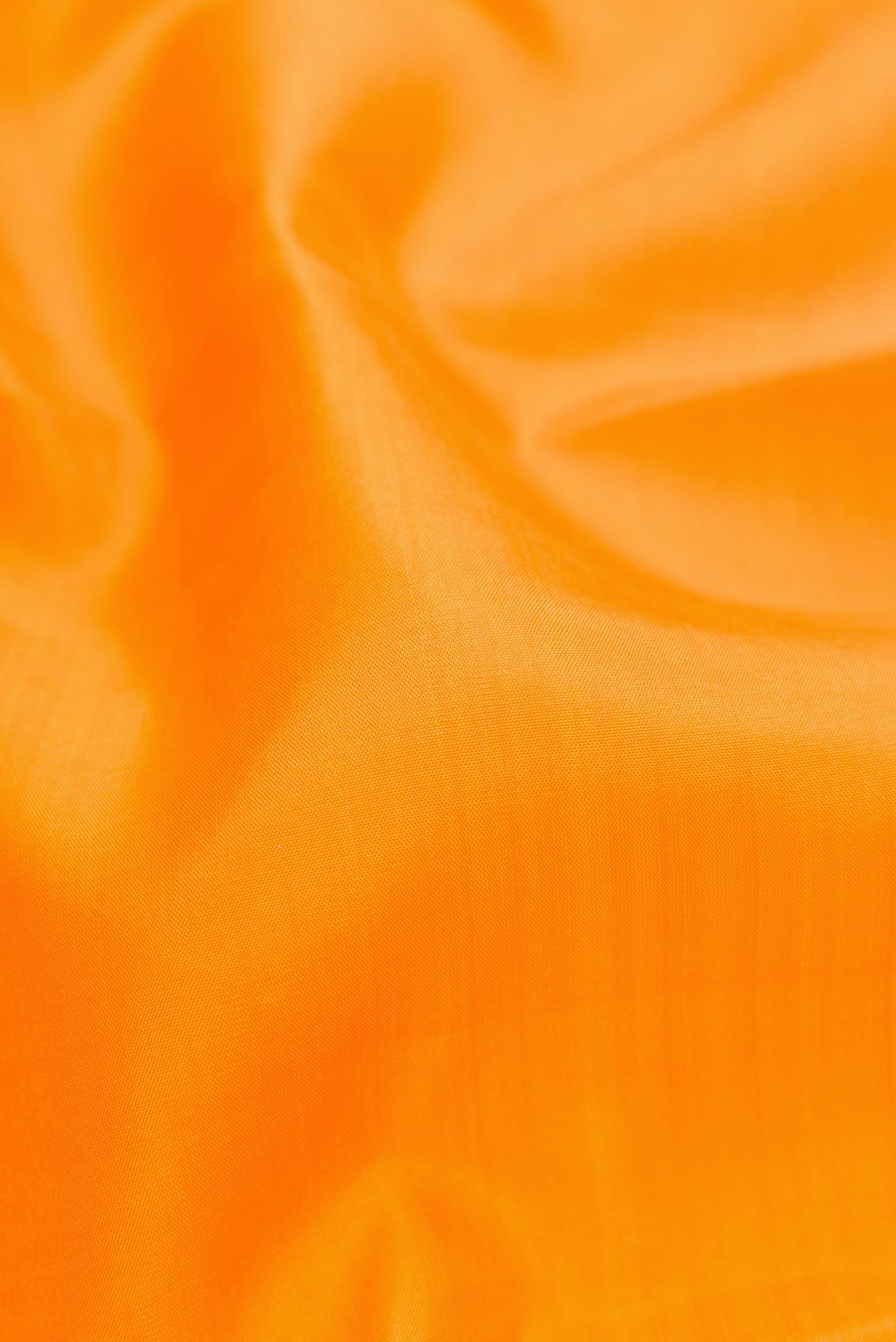 Close up of Orange Dual Tone Kanjivaram Silk Saree with Plain Body and Zari Border.  displaying folds