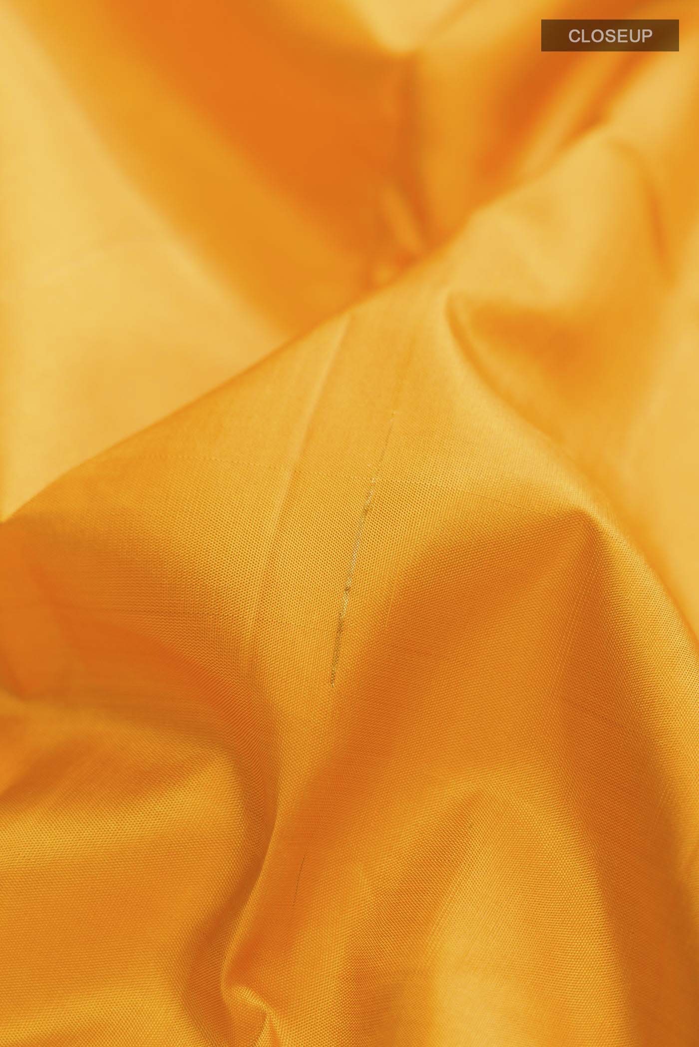 Close up of Yellow Kanchipuram Silk Saree with Zari Butta on the body and Zari Border displaying folds