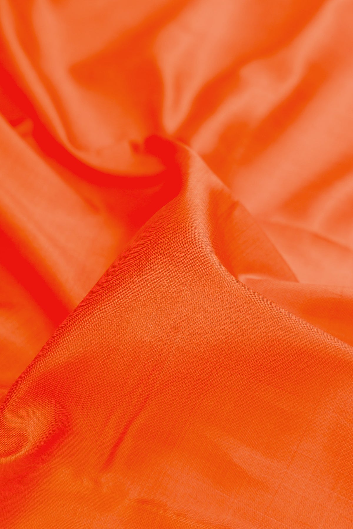Close up of Orange Dual Tone Kanchipuram Silk Saree with Plain Body and Thread Border.  displaying folds