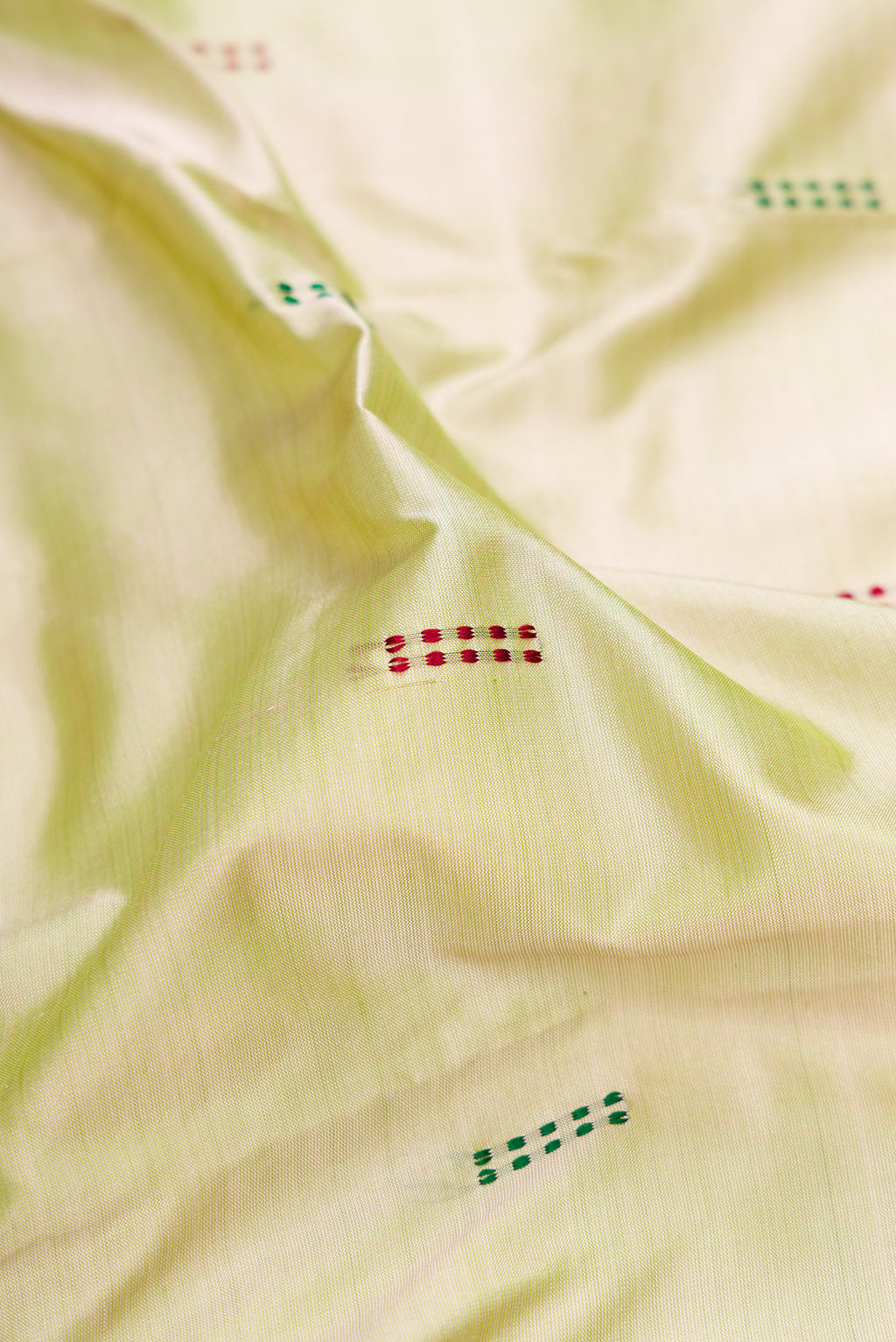 Close up of Light Green Kanchipuram Silk Saree with Thread Butta on the body and Thread Border.  displaying folds