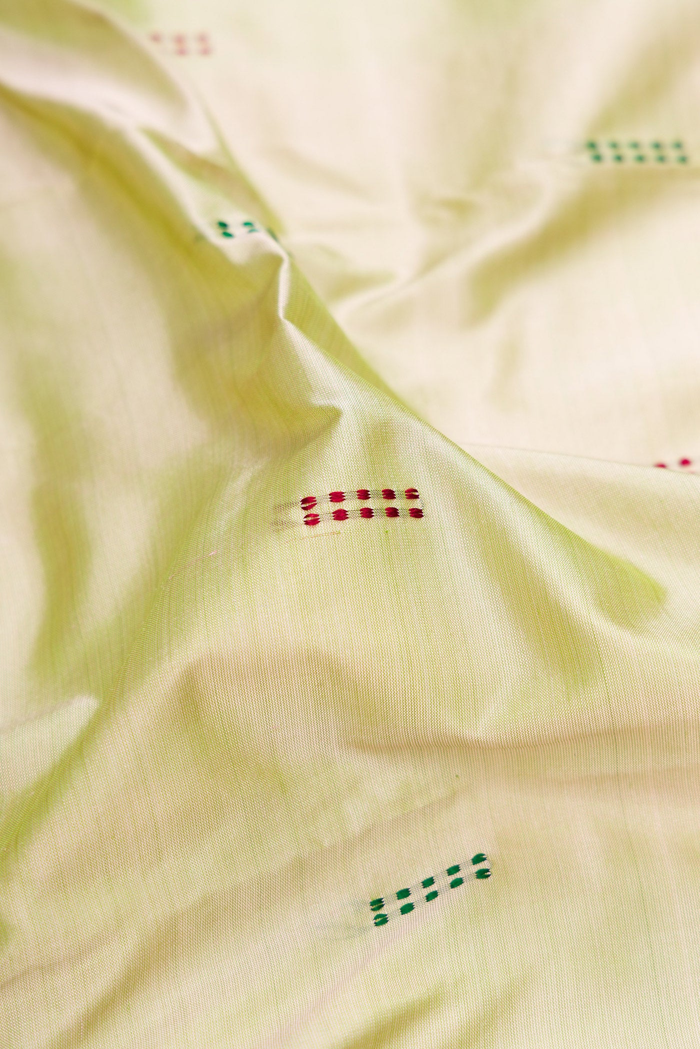 Close up of Light Green Kanchipuram Silk Saree with Thread Butta on the body and Thread Border.  displaying folds