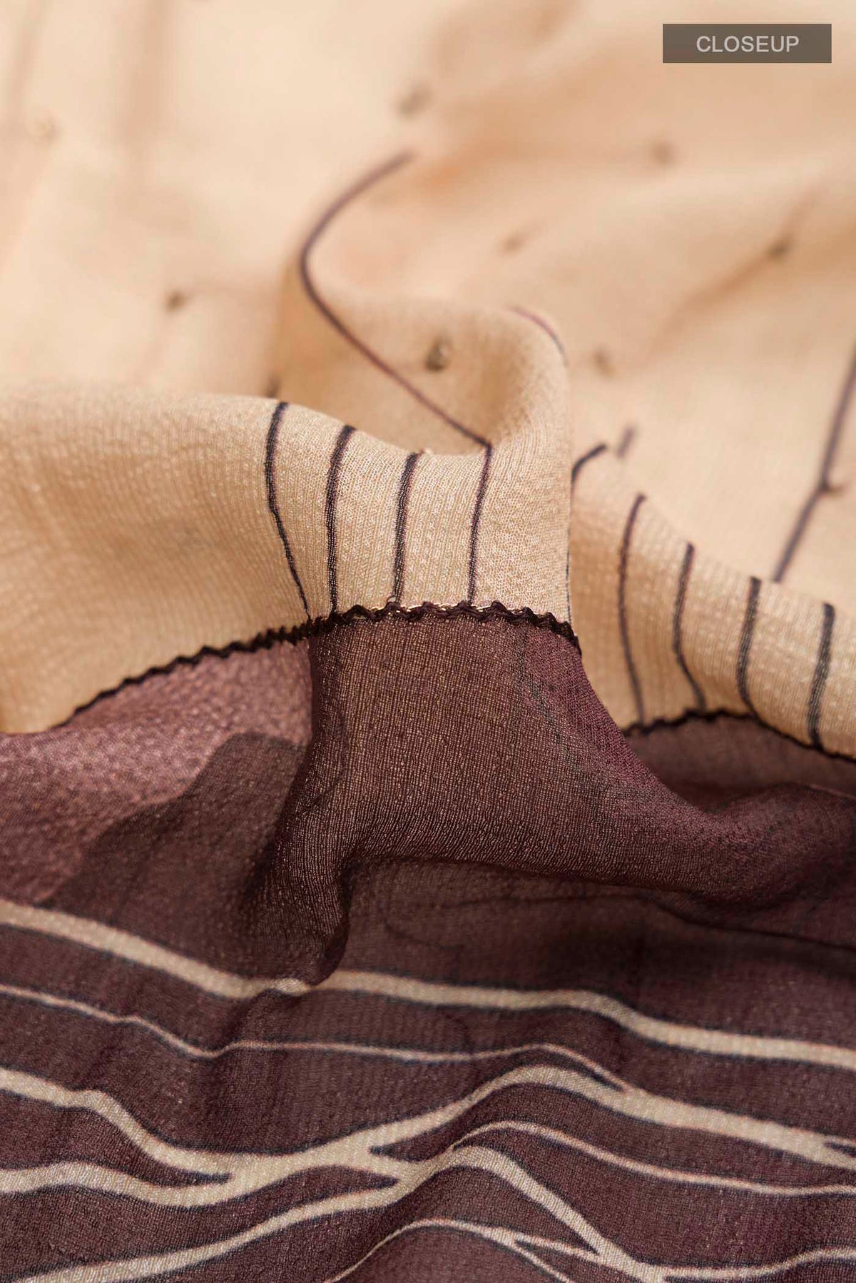 Close up of Beige Tussar Silk Saree with Embroidery on the body and Zari Border displaying folds