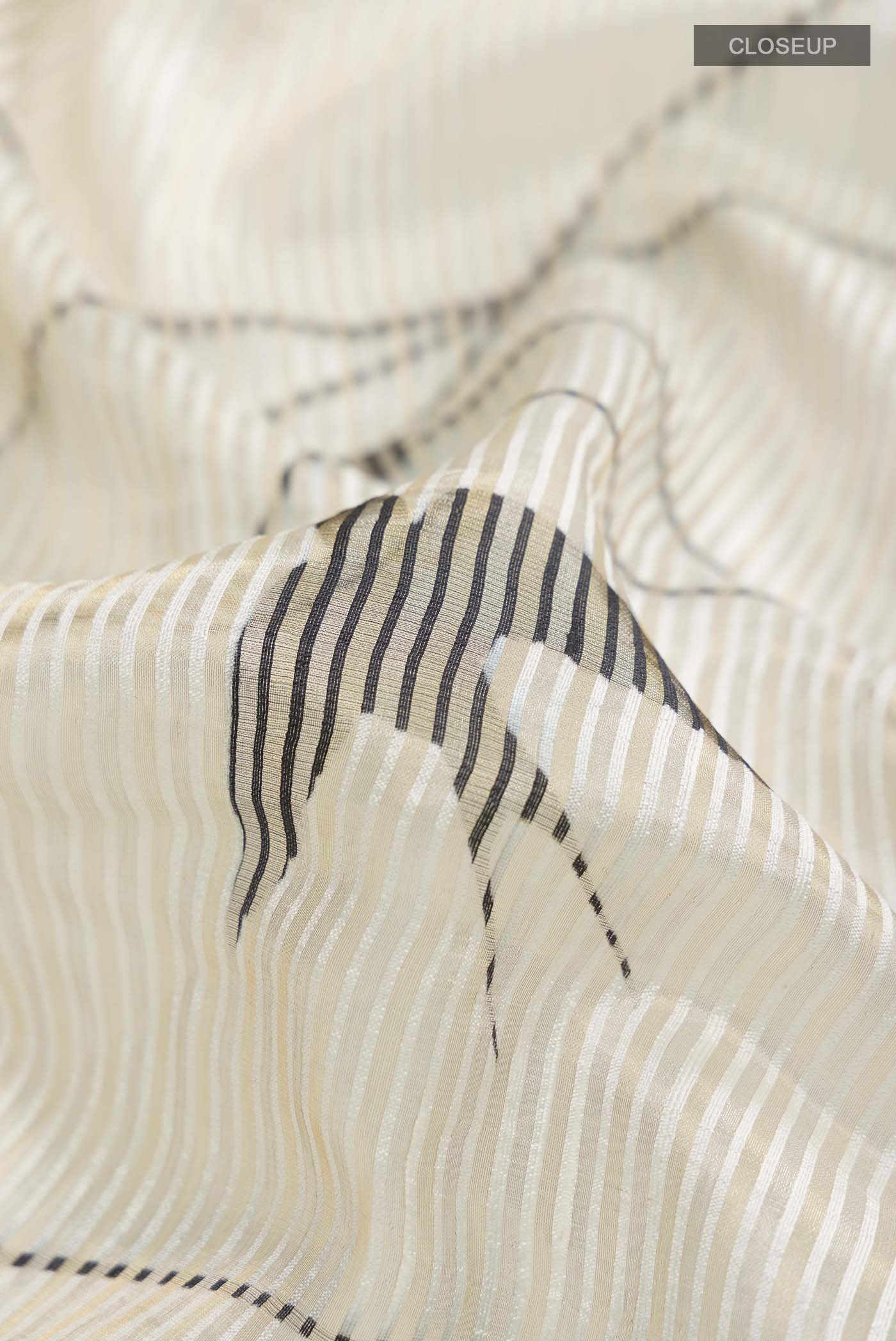 Close up of Off White Kora Silk Saree with Stripes on the body and Zari Border displaying folds