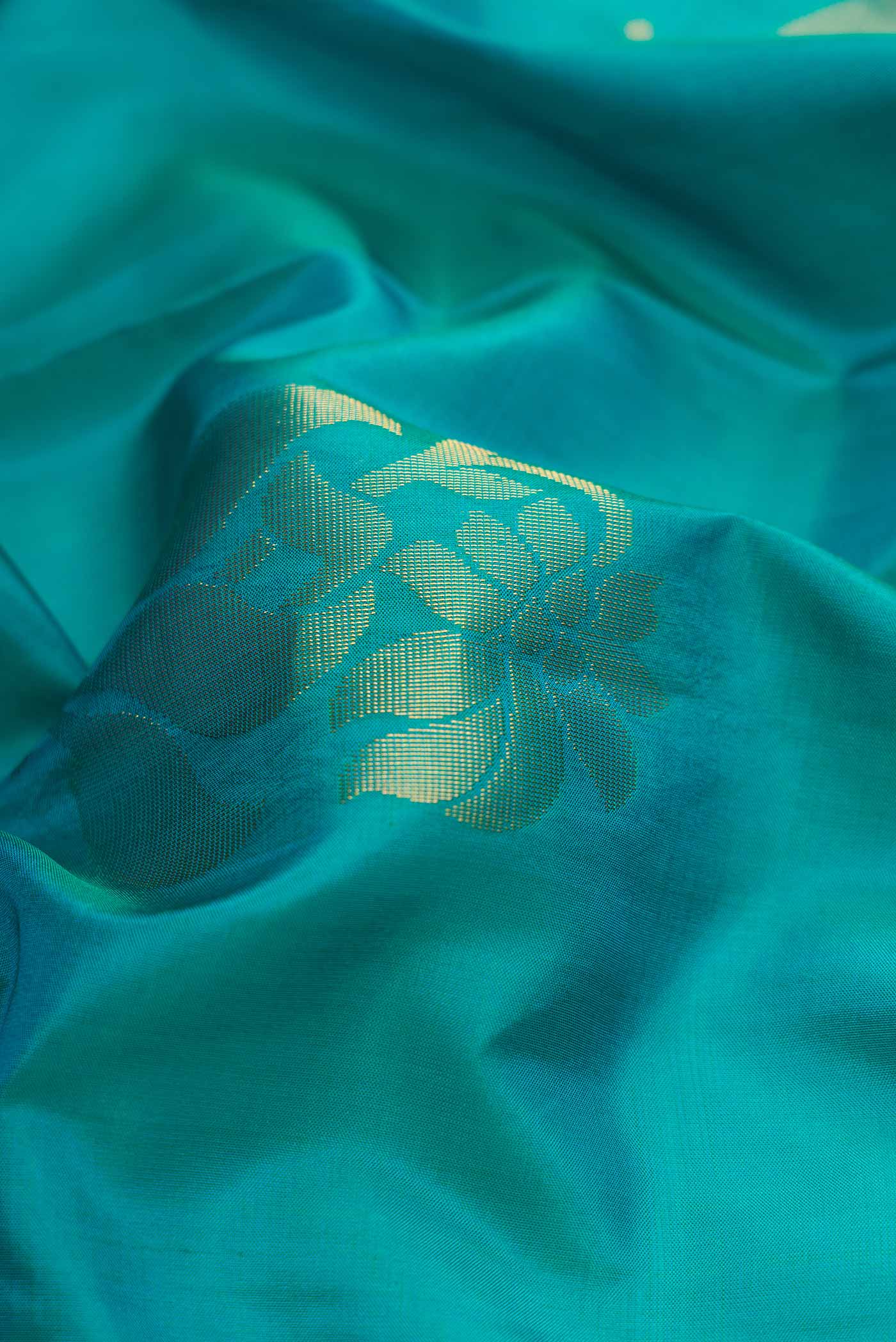 Close up of Peacock Blue Dual Tone Soft Silk Saree with Zari Butta on the body and Zari Border.  displaying folds