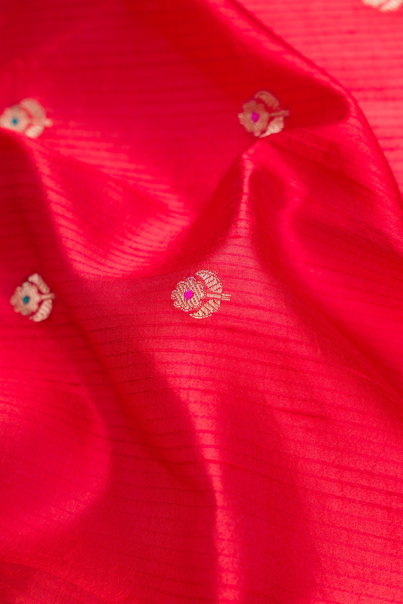 Close up of Red Dual Tone Tussar Silk Saree with Zari Butta on the body and Fancy Border.  displaying folds