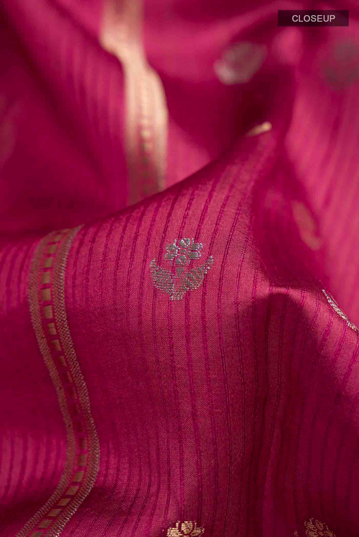 Close up of Magenta Banarasi Raw Silk Saree with Zari Butta on the body and Zari Border displaying folds