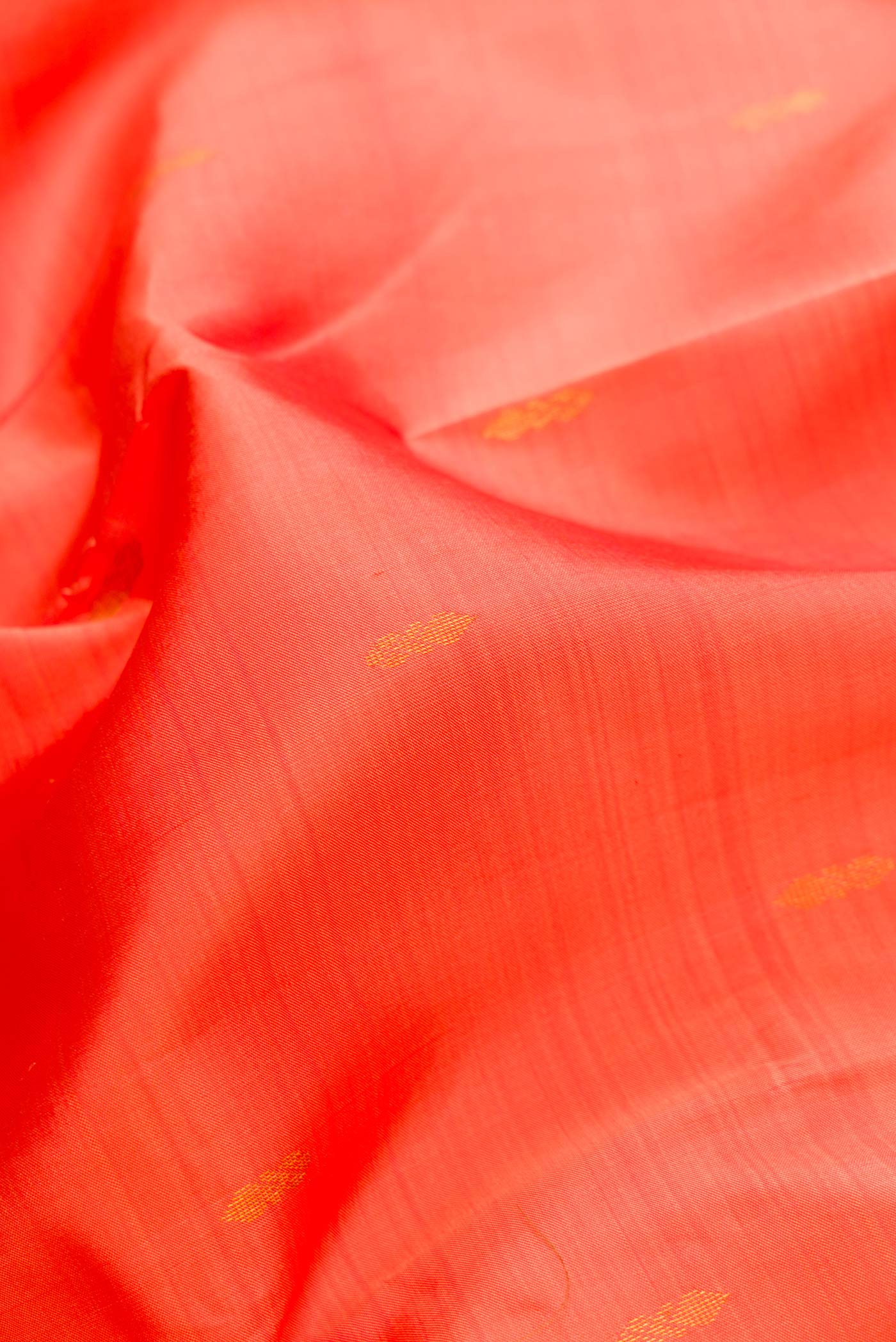 Close up of Peach Dual Tone Kanchipuram Silk Saree with Zari Butta on the body and Zari Border.  displaying folds