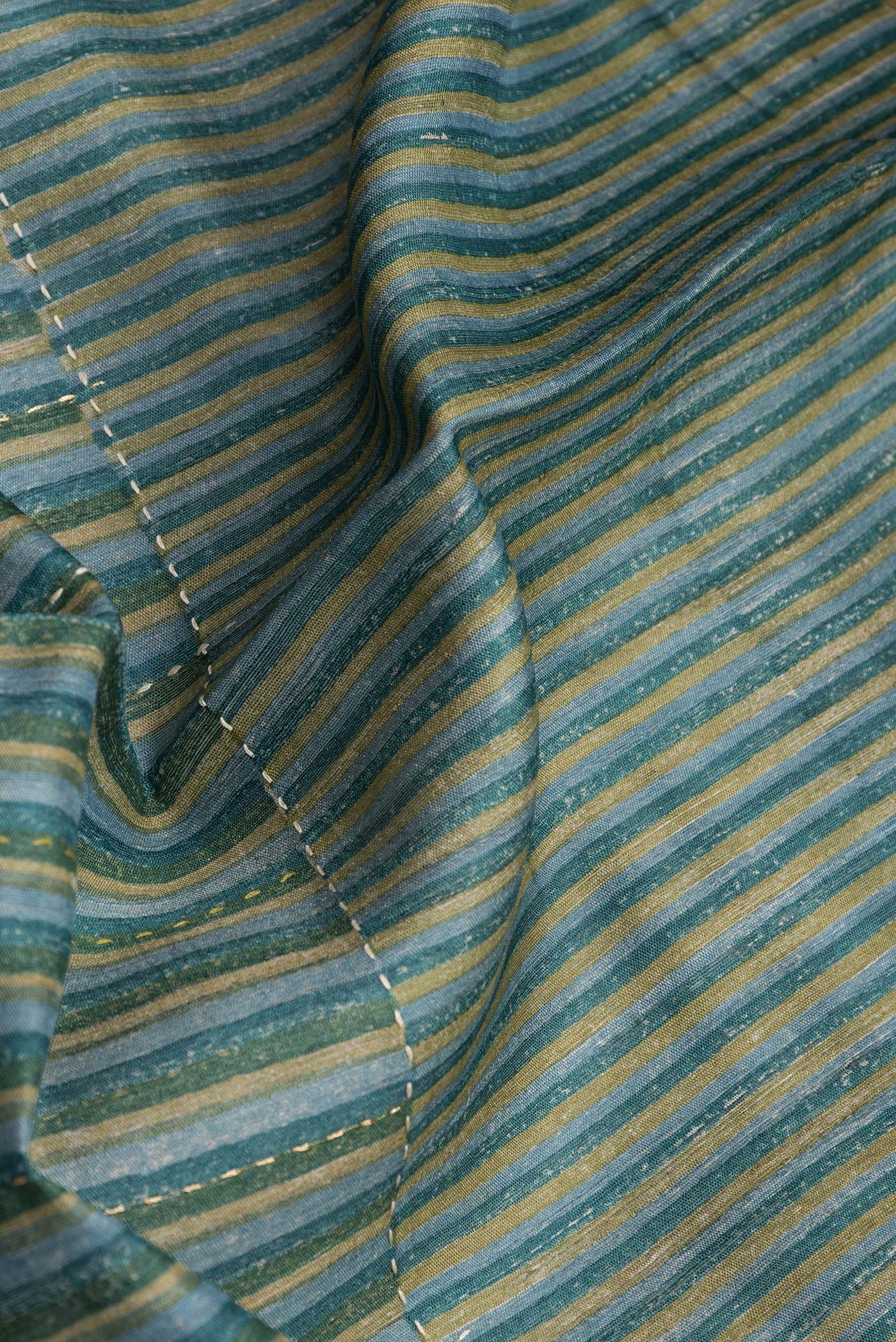 Close up of Mehandi Green Tussar Silk Saree with Embroidery on the body and Zari Border.  displaying folds
