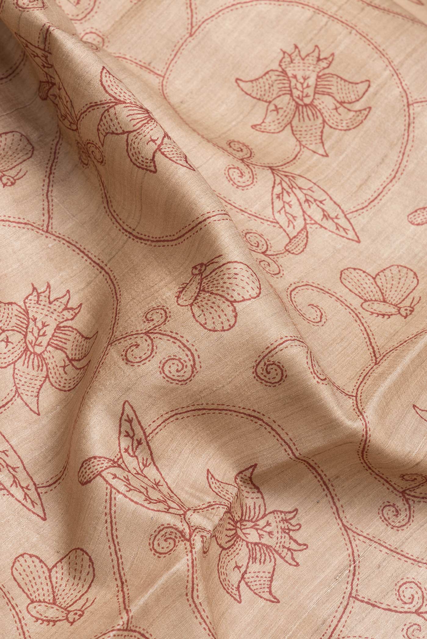 Close up of Beige Dual Tone Tussar Silk Saree with Printed design on the body and Embroidery Border.  displaying folds