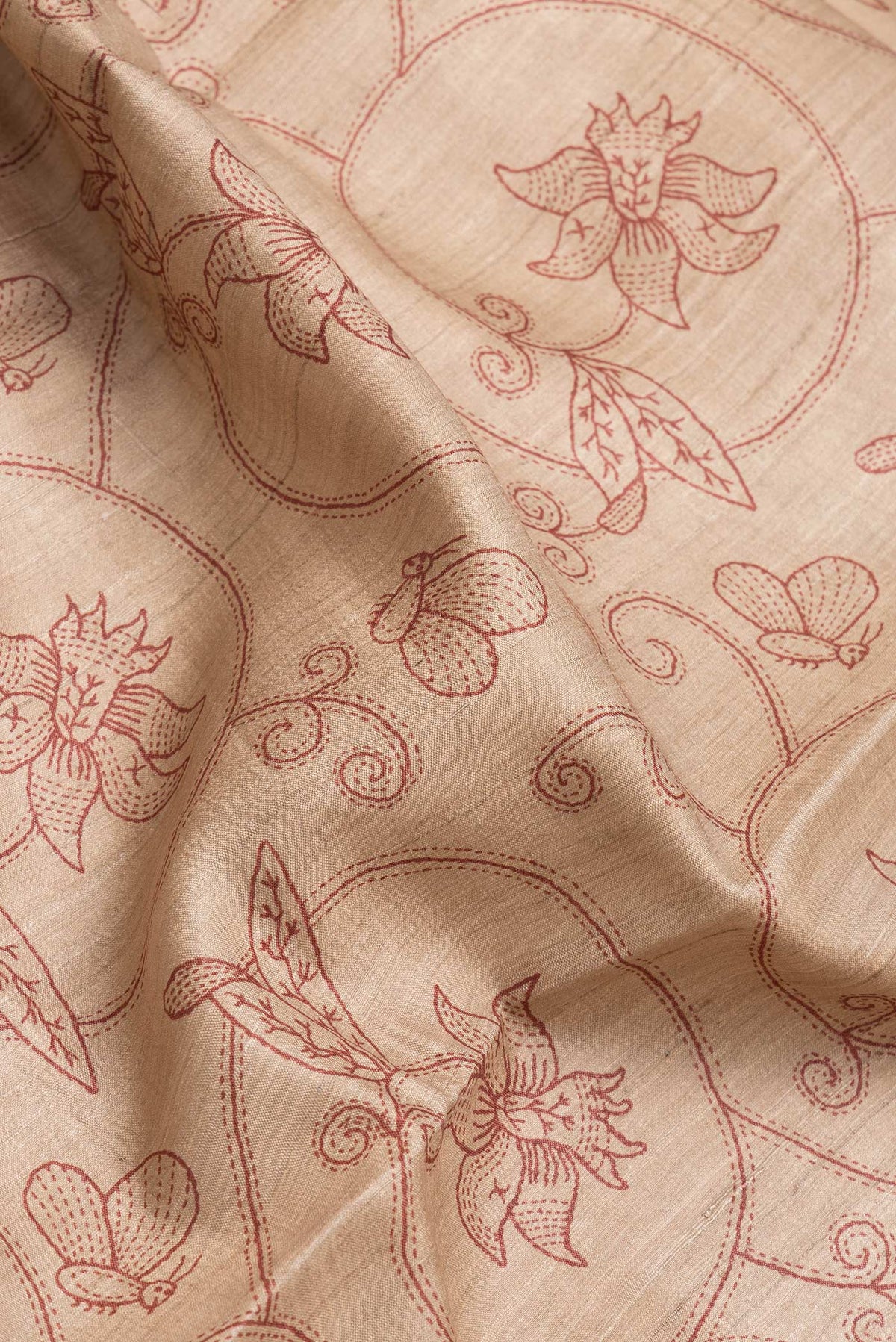 Close up of Beige Dual Tone Tussar Silk Saree with Printed design on the body and Embroidery Border.  displaying folds