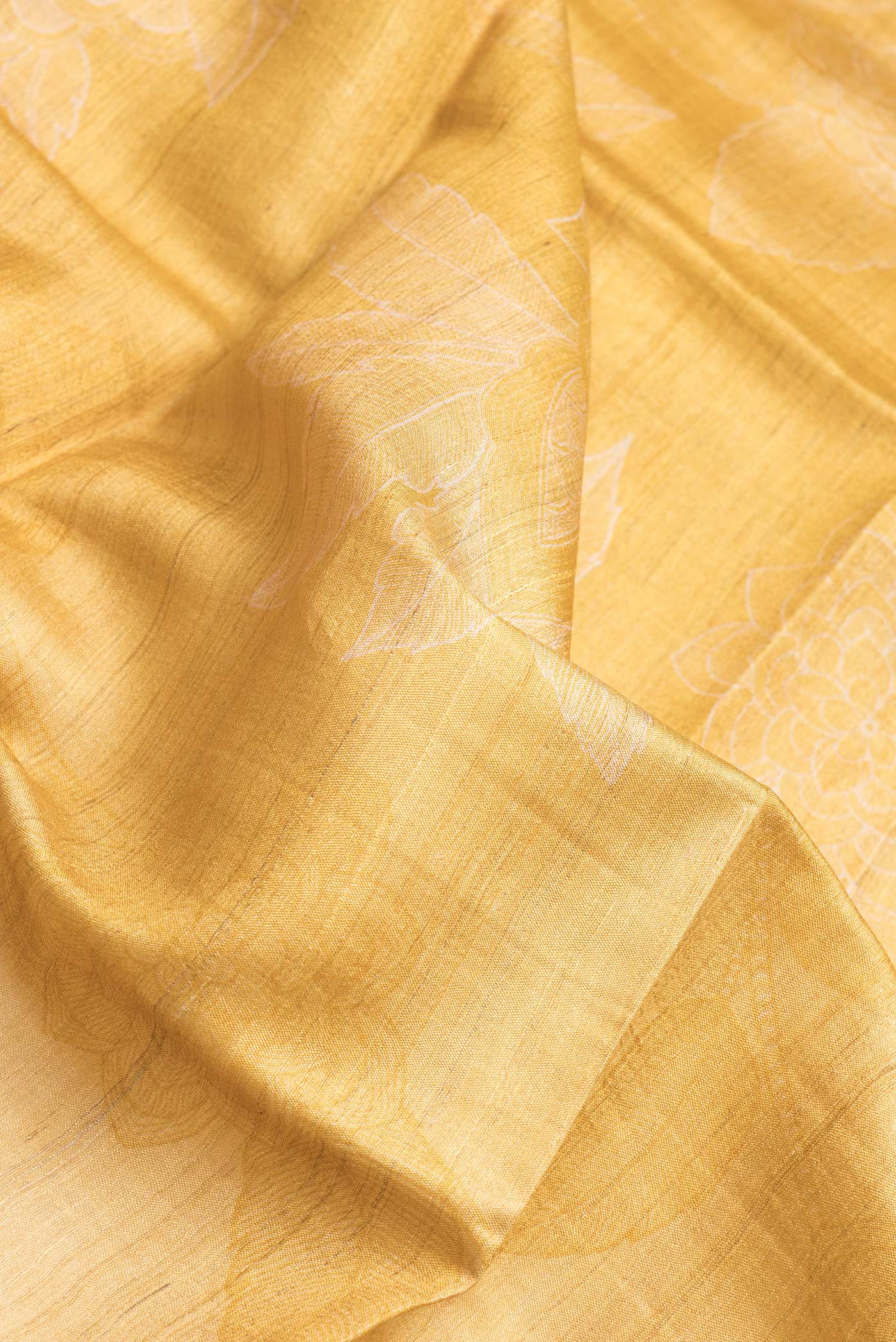 Close up of Mustard Dual Tone Tussar Silk Saree with Printed design on the body and Embroidery Border.  displaying folds