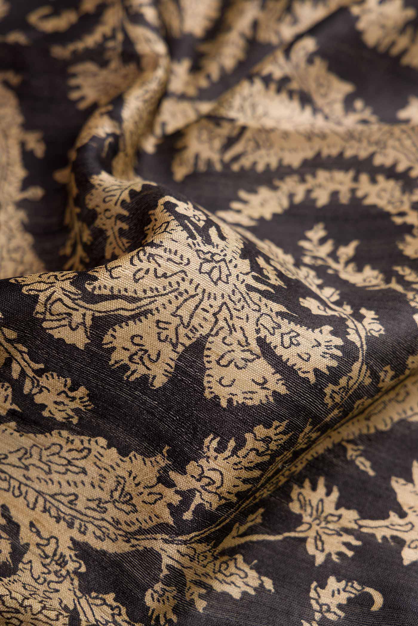Close up of Black Dual Tone Tussar Silk Saree with Printed design on the body and Embroidery Border.  displaying folds