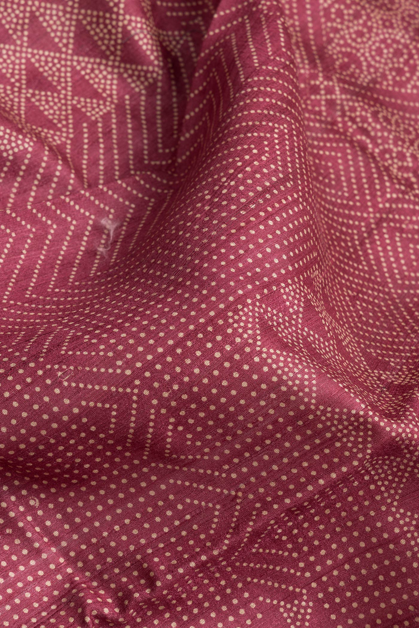Close up of Maroon Dual Tone Tussar Silk Saree with Printed design on the body and Zari And Thread Border.  displaying folds