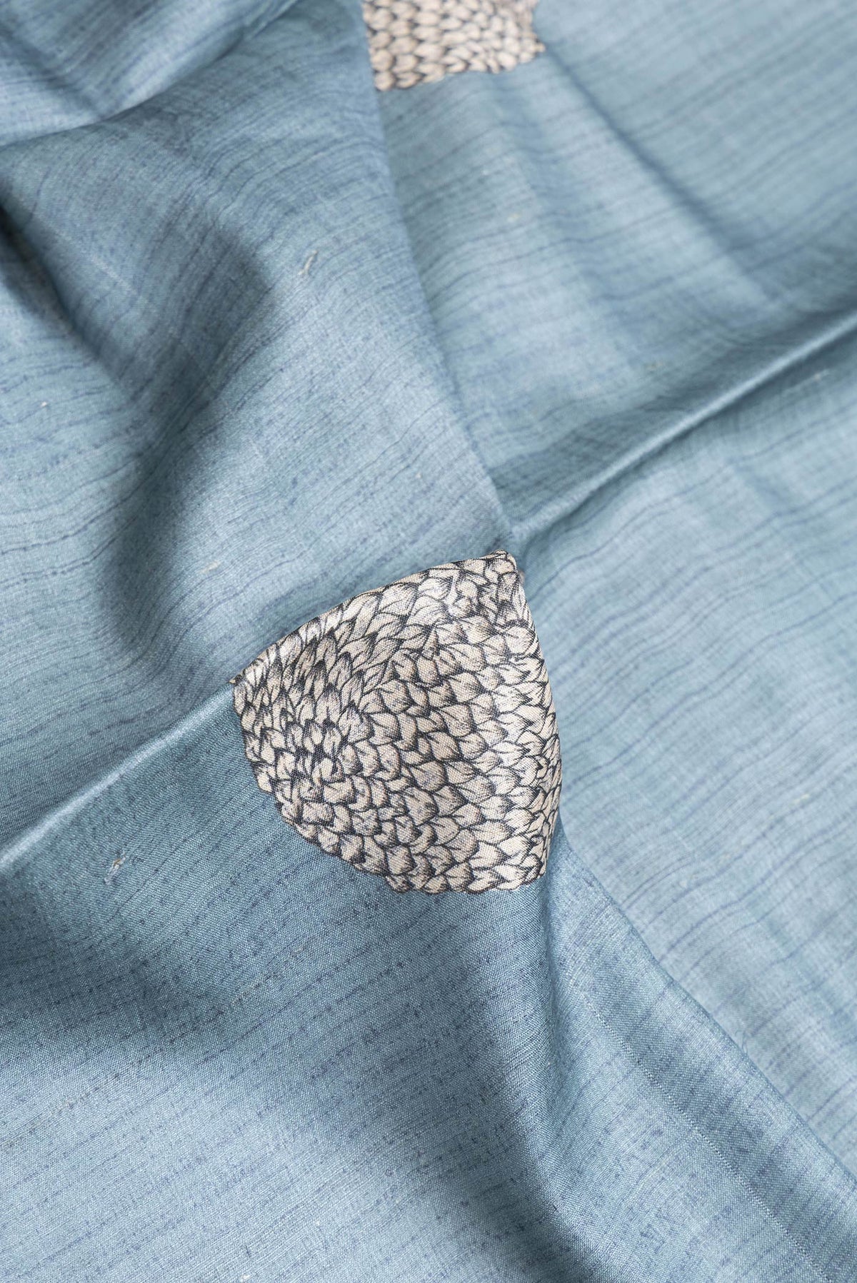 Close up of Grey Dual Tone Tussar Silk Saree with Printed design on the body and Embroidery Border.  displaying folds