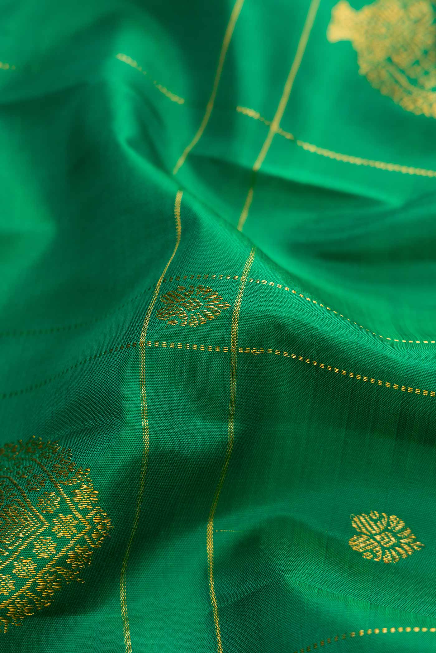 Close up of Green Dual Tone Kanchipuram Silk Saree with Zari Butta on the body and Zari Border displaying folds