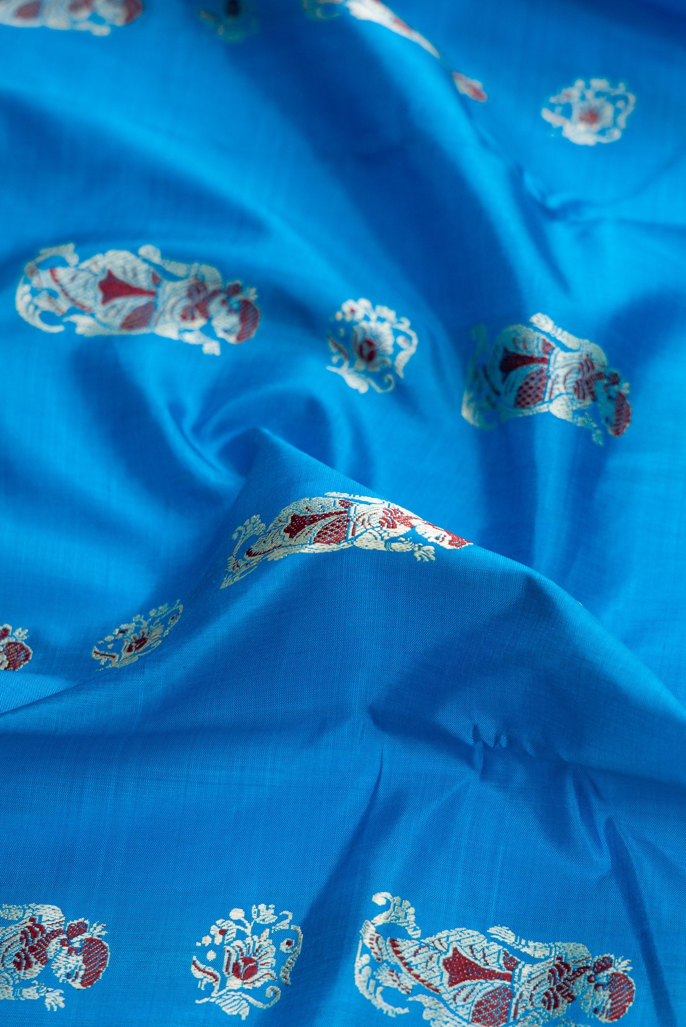 Close up of Sky Blue Dual Tone Baluchari Silk Saree with Thread Butta on the body and Thread Border.  displaying folds