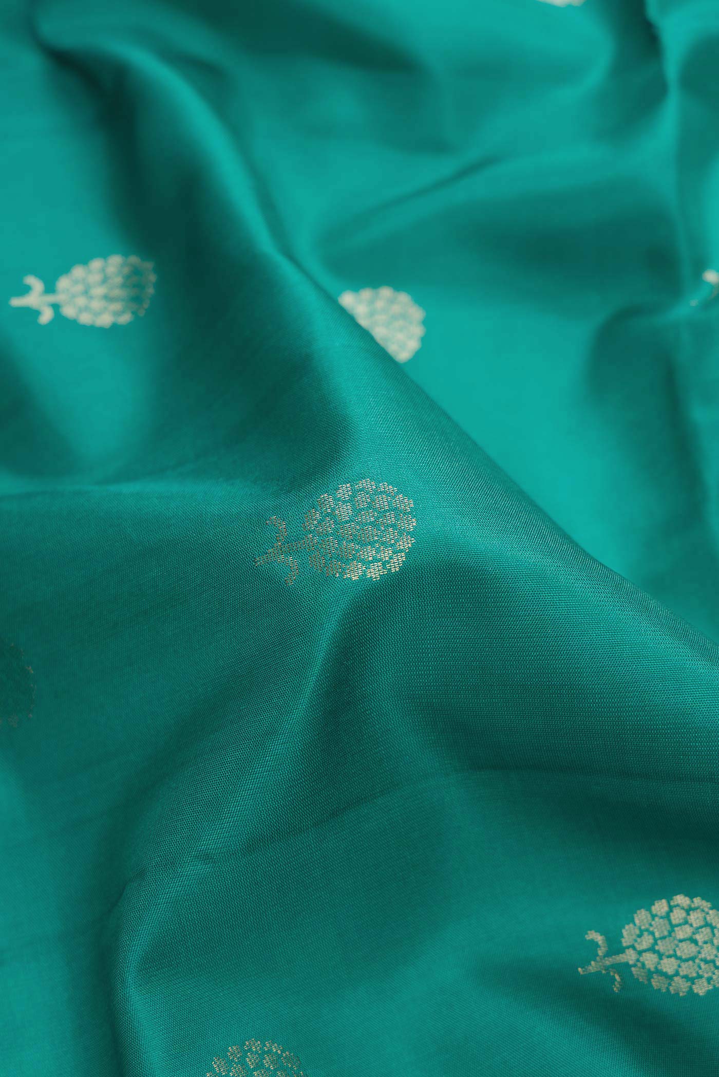 Close up of Green Dual Tone Soft Silk Saree with Zari Butta on the body and Zari Border.  displaying folds
