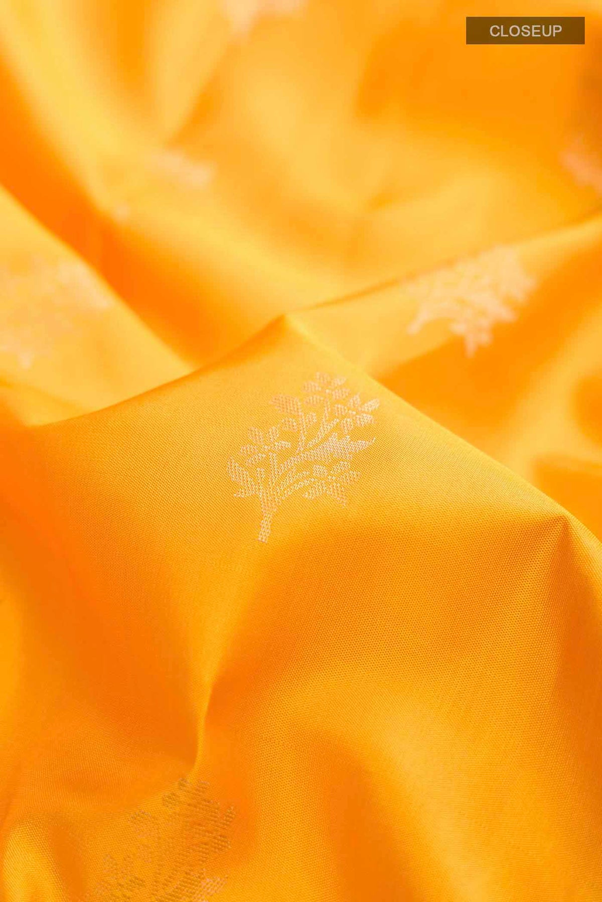 Close up of Yellow Soft Silk Saree with Zari Butta on the body and Zari Border displaying folds