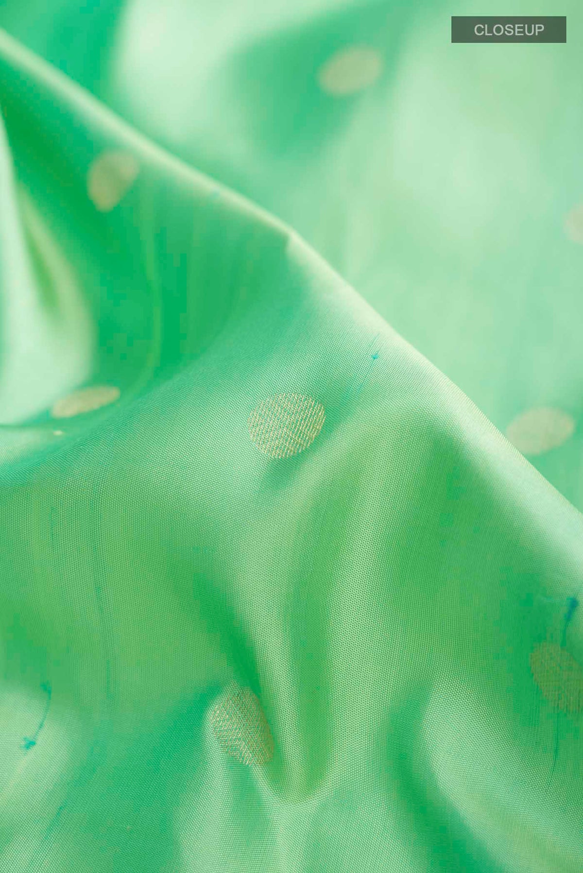 Close up of Green Soft Silk Saree with Zari Butta on the body and Zari Border displaying folds