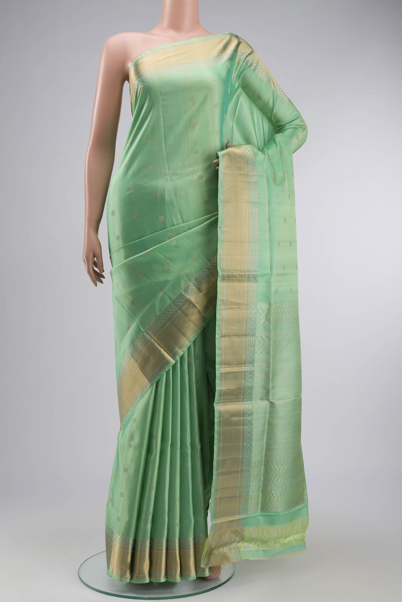 Green Soft Silk Saree with Zari Butta on the body and Zari Border displayed on a mannequin