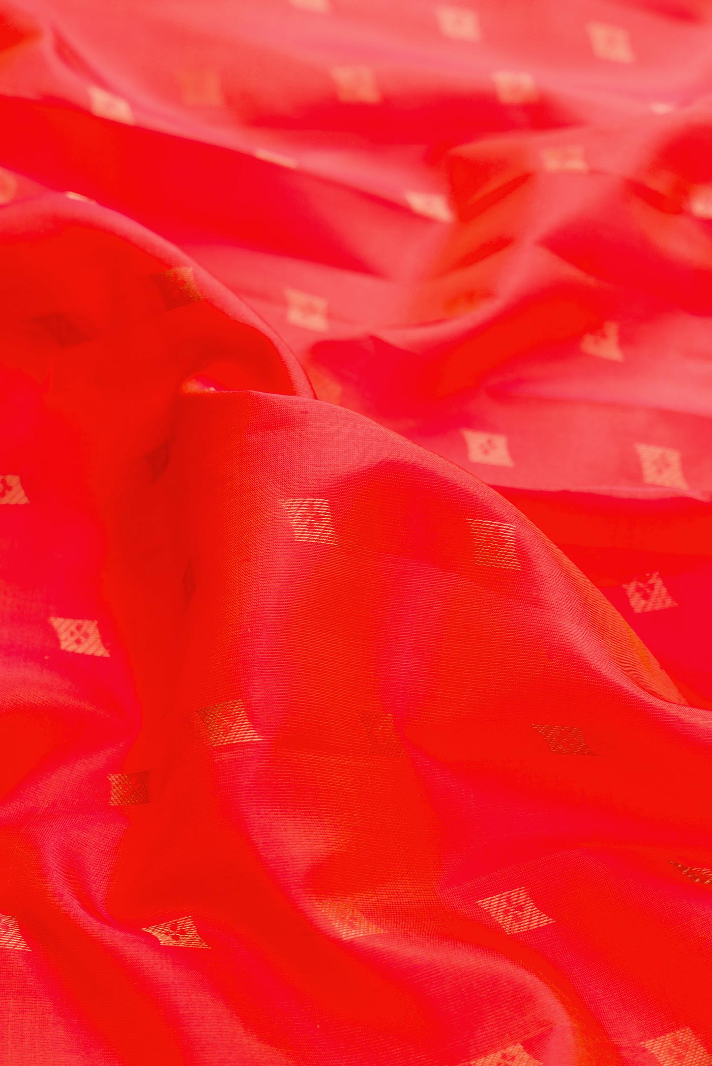 Close up of Orange Dual Tone Kanchipuram Silk Saree with Zari Butta on the body and Zari Border displaying folds