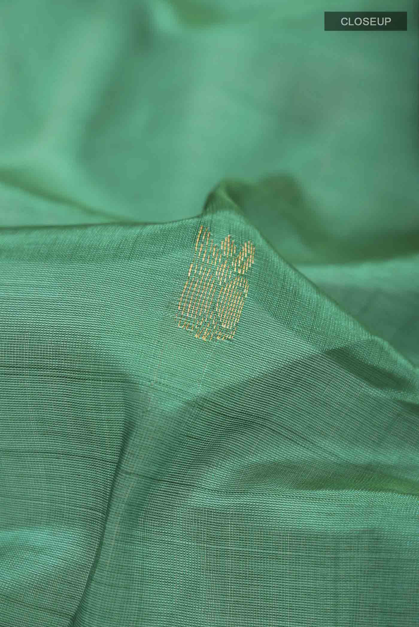 Close up of Green Silk Cotton Saree with Zari Butta on the body and Zari Border displaying folds