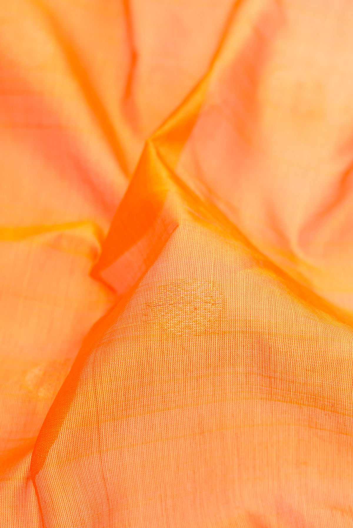 Close up of Orange Silk Cotton Saree with Zari Butta on the body and Zari Border.  displaying folds