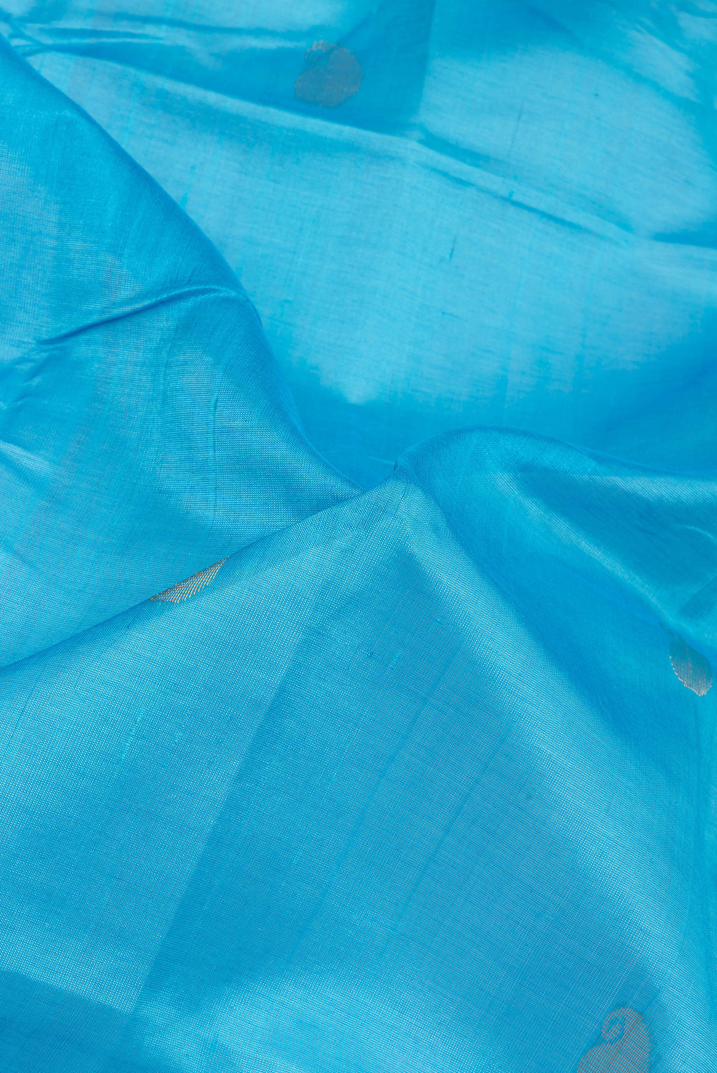 Close up of Sky Blue Silk Cotton Saree with Zari Butta on the body and Zari Border.  displaying folds