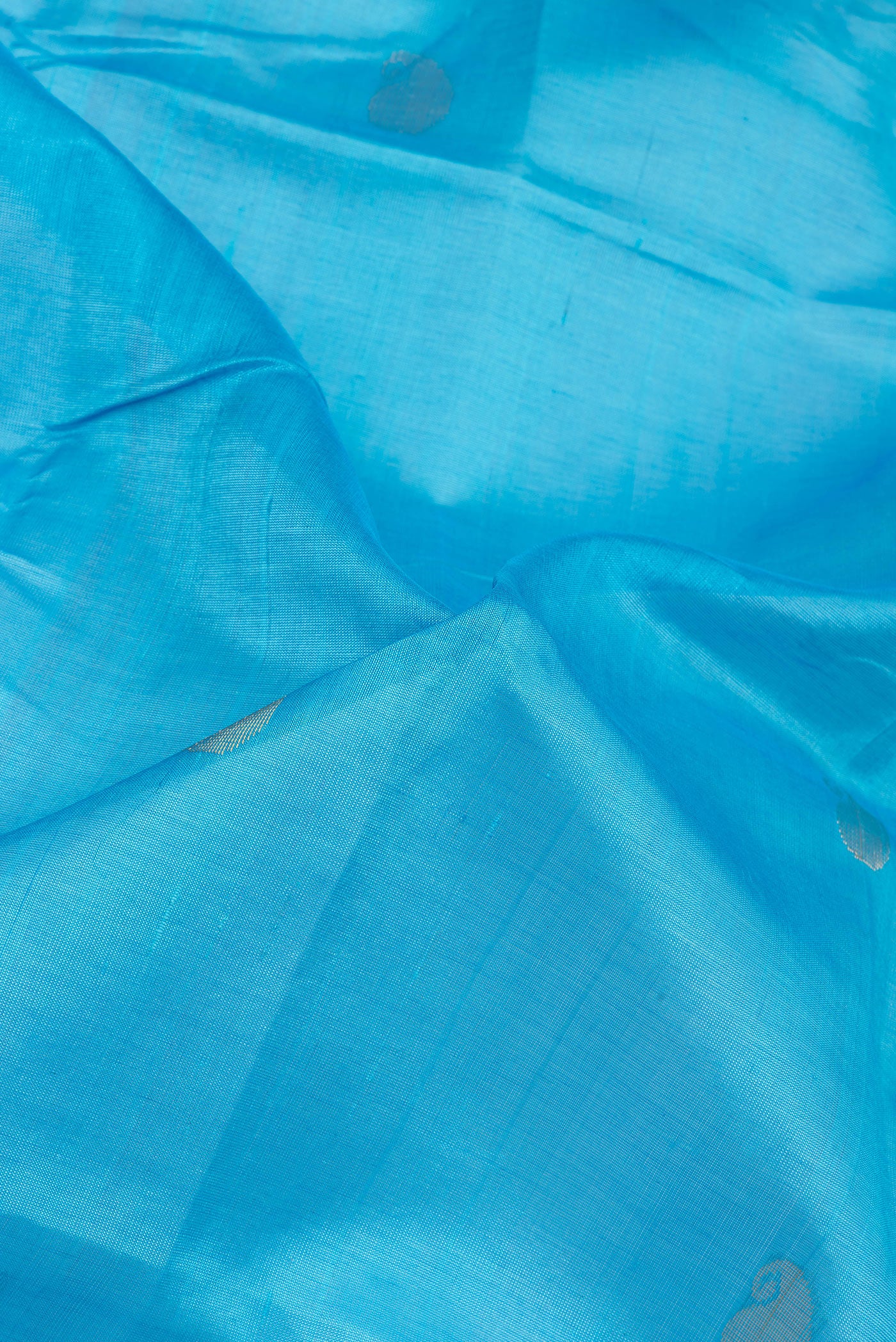 Close up of Sky Blue Silk Cotton Saree with Zari Butta on the body and Zari Border.  displaying folds