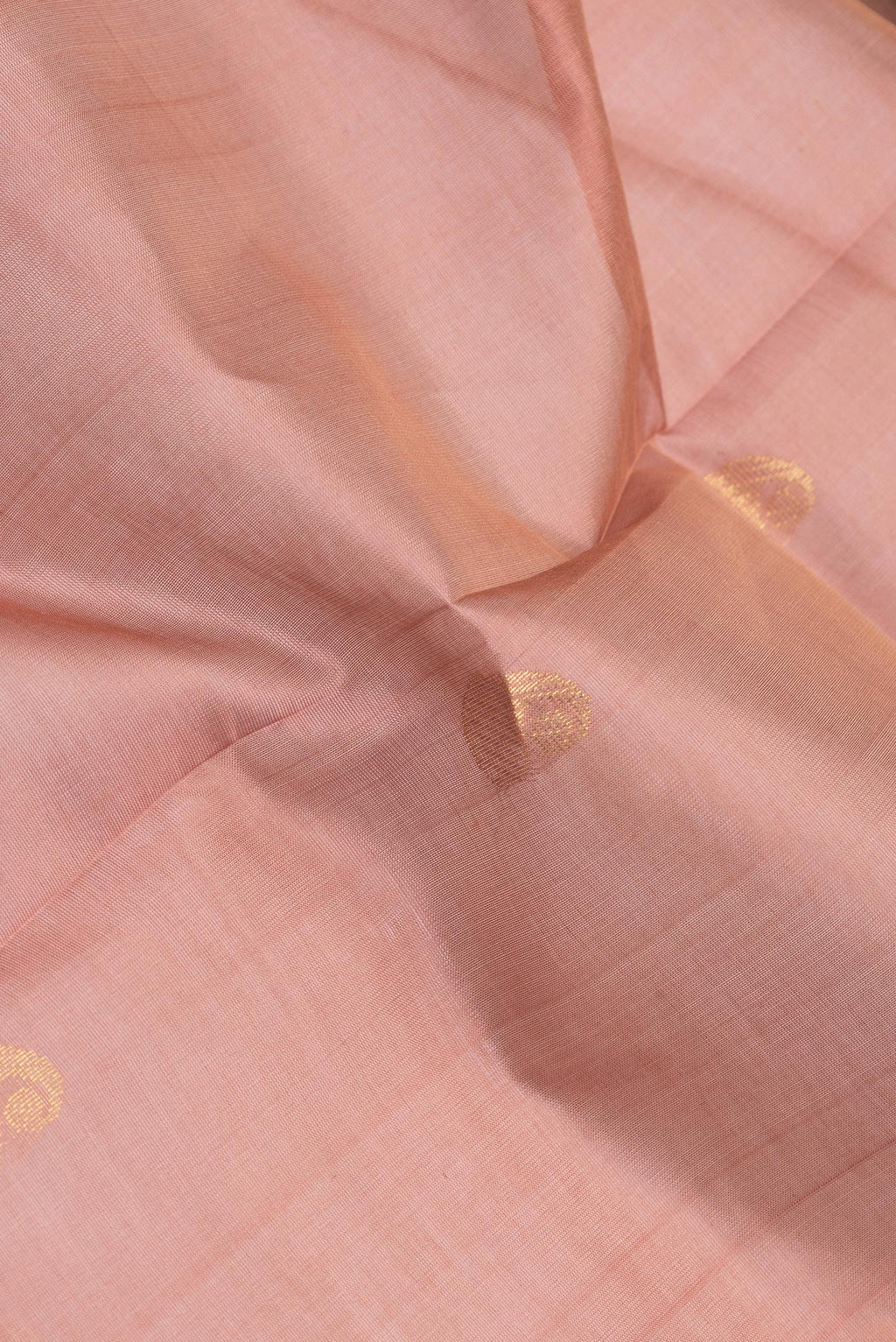 Close up of Rose Gold Silk Cotton Saree with Zari Butta on the body and Zari Border.  displaying folds