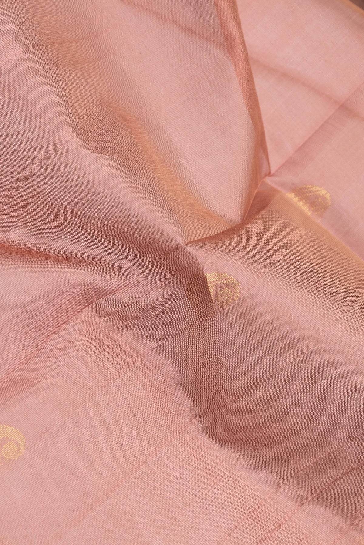 Close up of Rose Gold Silk Cotton Saree with Zari Butta on the body and Zari Border.  displaying folds