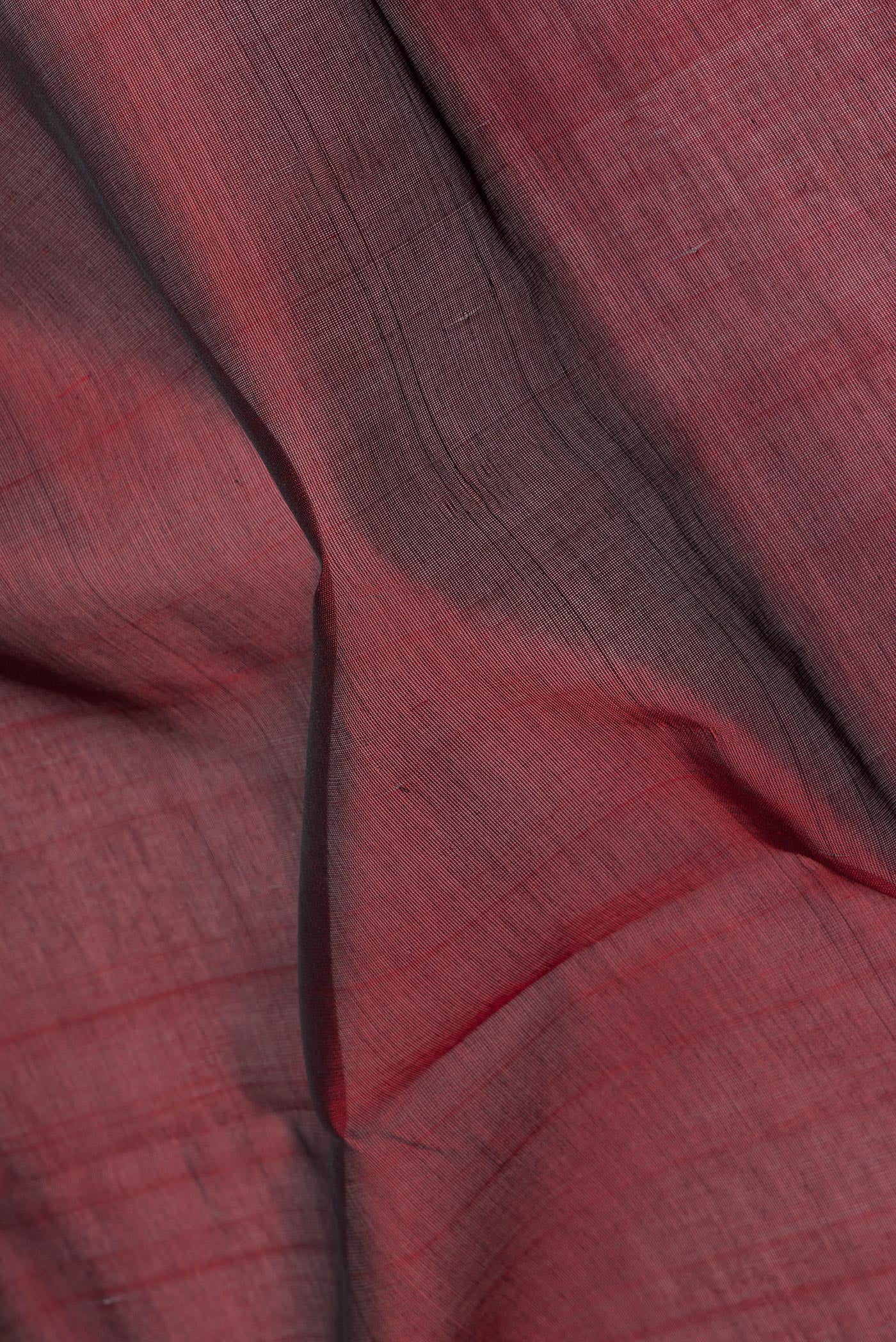 Close up of Maroon Silk Cotton Saree with Plain Body and Zari Border.  displaying folds