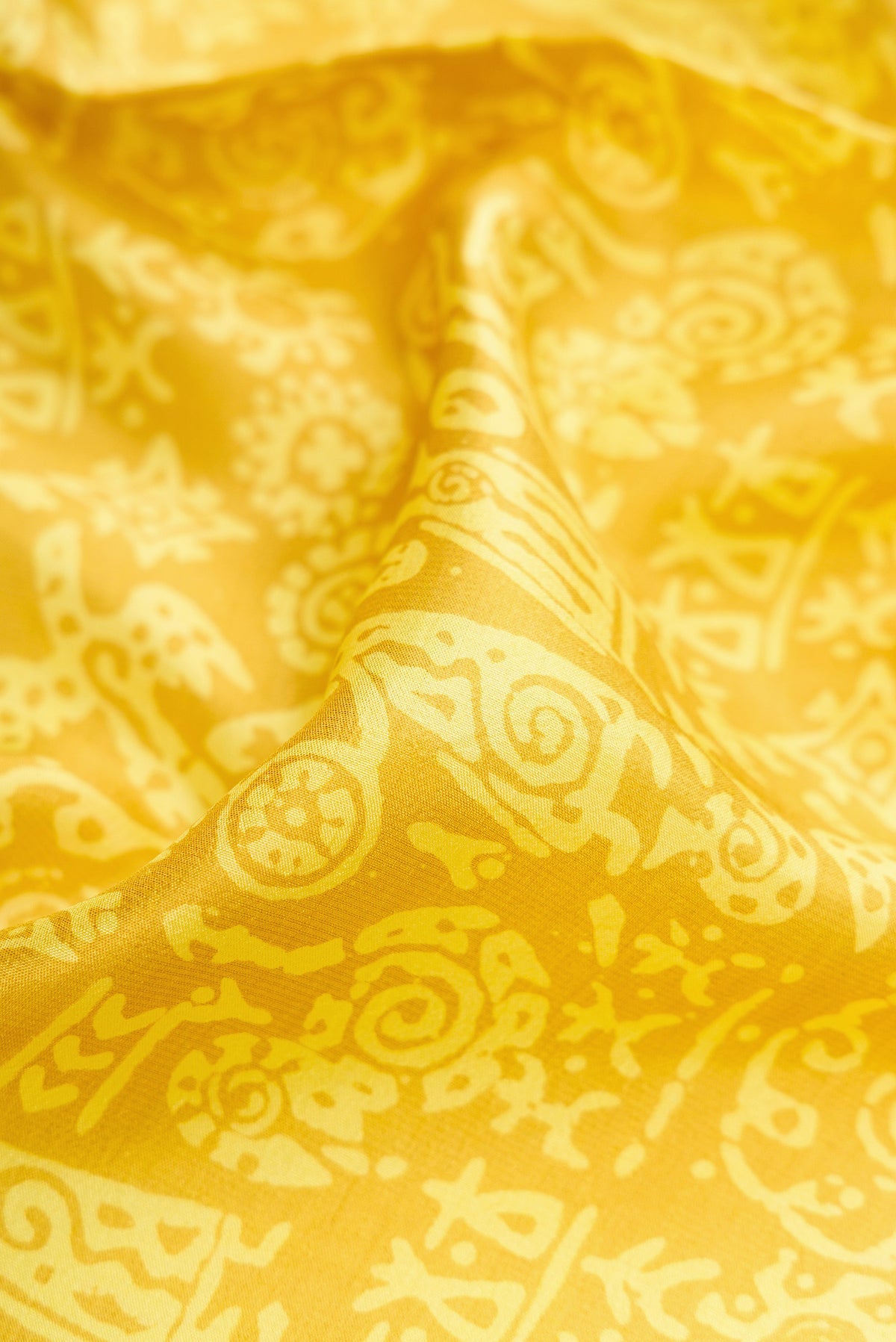 Close up of Yellow Printed Silk Saree with Printed design on the body and Printed Border.  displaying folds