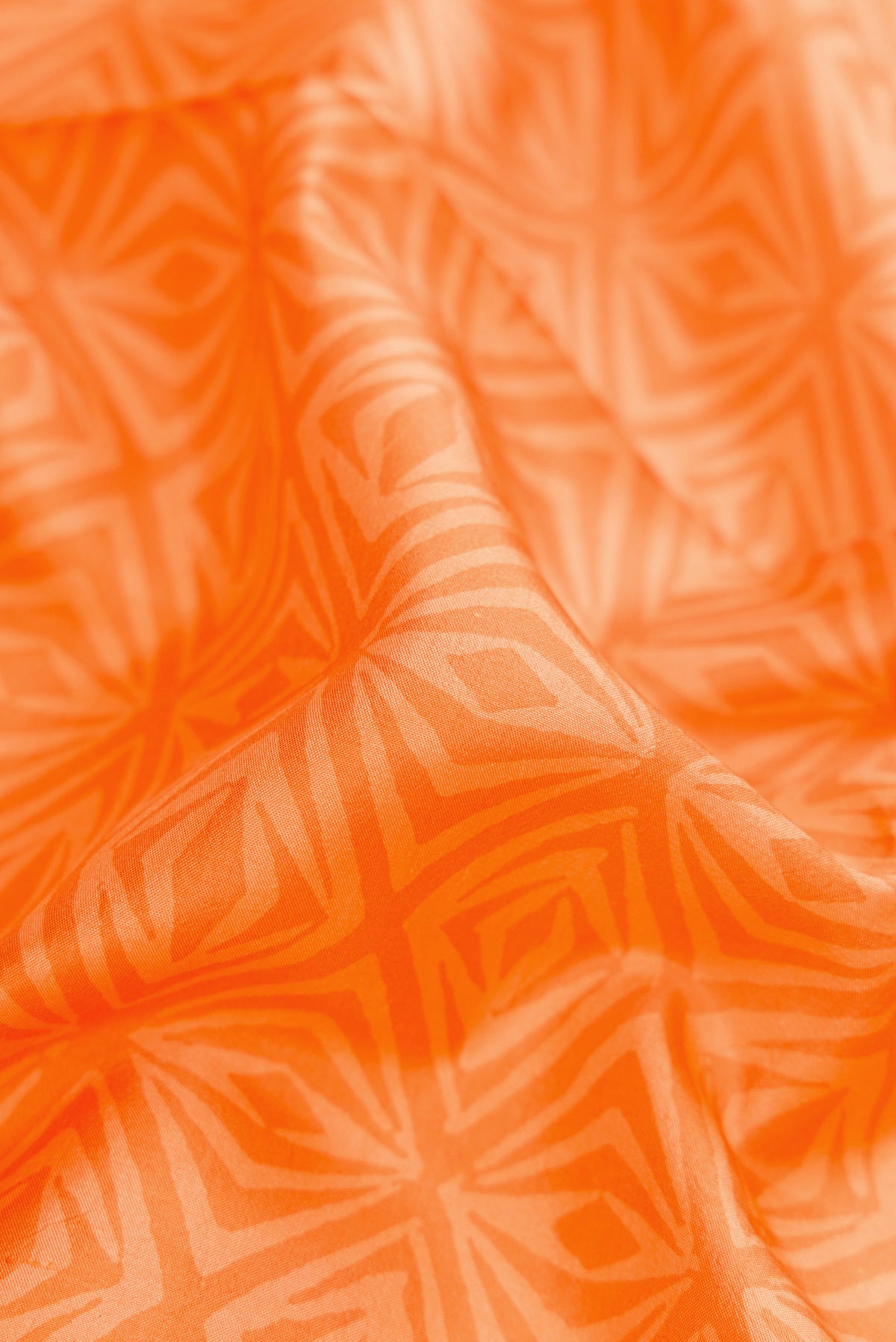 Close up of Orange Dual Tone Printed Silk Saree with Printed design on the body and Printed Border.  displaying folds