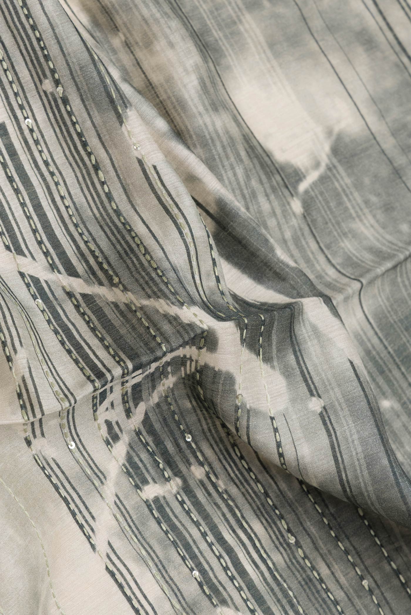 Close up of Beige Dual Tone Tussar Silk Saree with Embroidery on the body and Zari Border.  displaying folds
