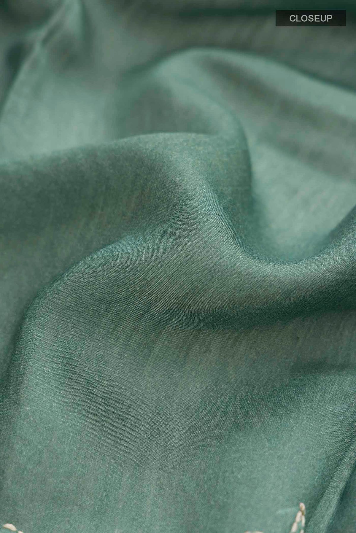 Close up of Sage Green Tussar Silk Saree with Embroidery on the body and Thread Border displaying folds