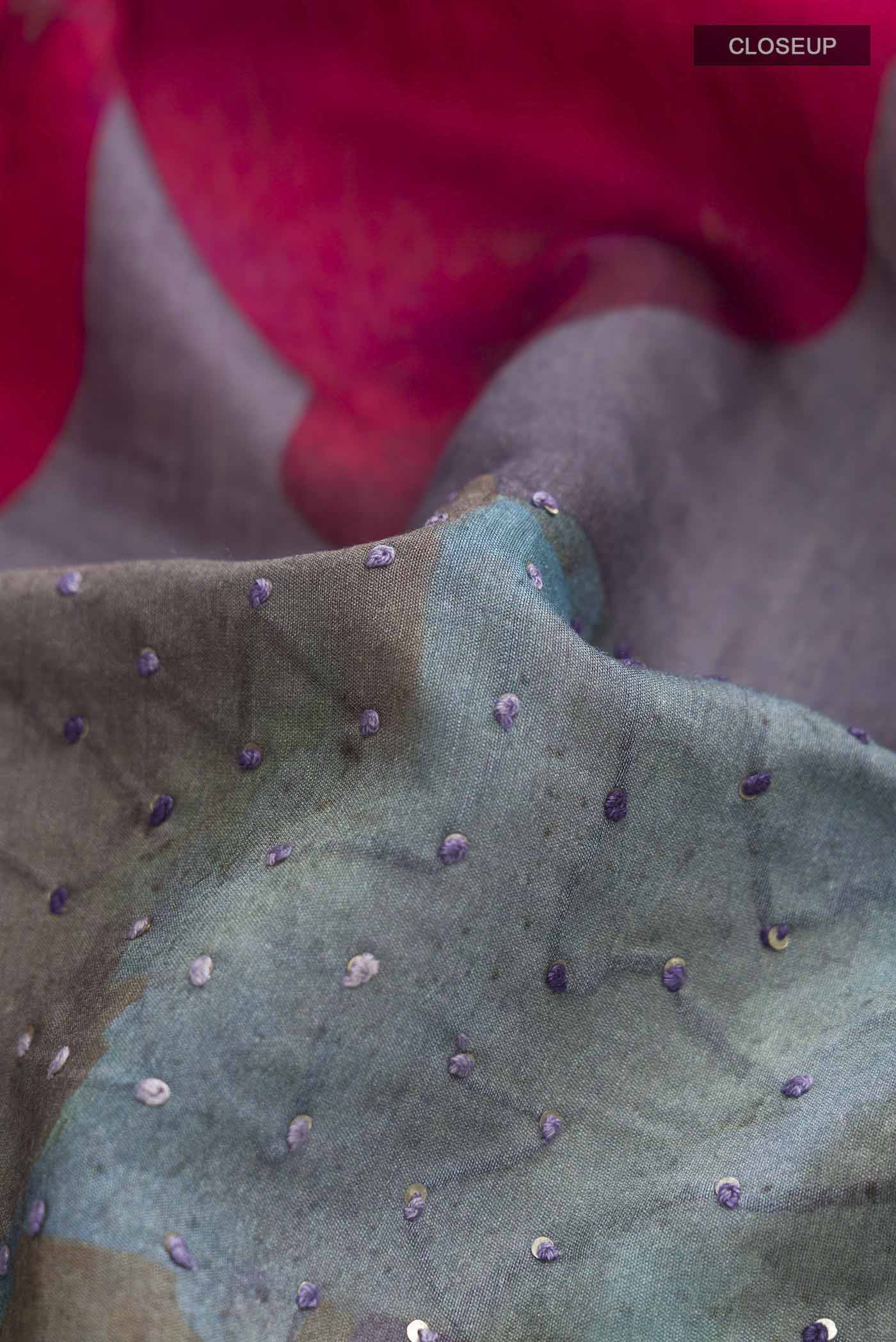 Close up of Grey Tussar Silk Saree with Embroidery on the body and Zari And Thread Border displaying folds