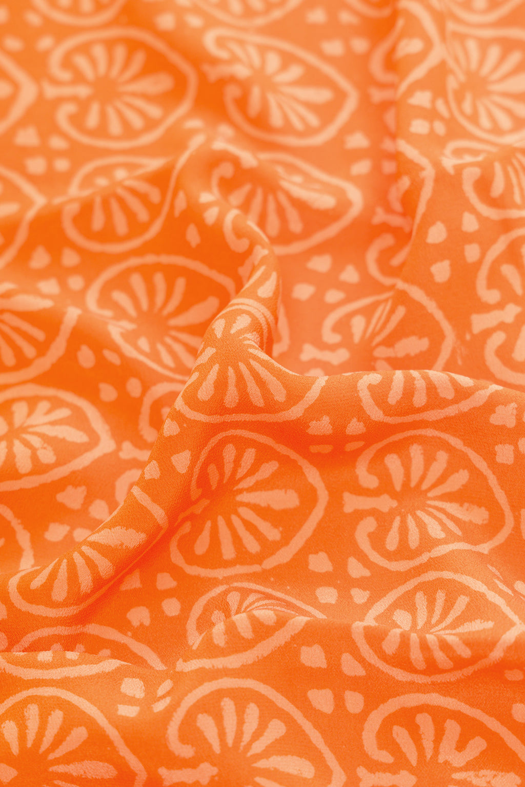 Close up of Orange Dual Tone Mysore Crepe Saree with Printed design on the body and Printed Border.  displaying folds