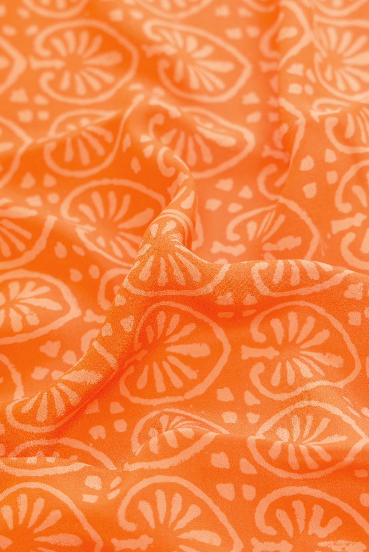 Close up of Orange Dual Tone Mysore Crepe Saree with Printed design on the body and Printed Border.  displaying folds